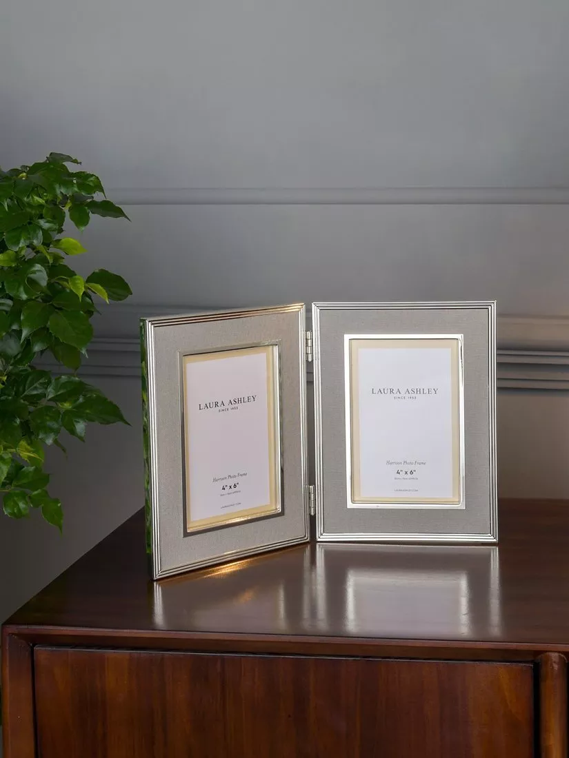 Silver mirrored photo frame on wooden sideboard with leafy plant and cream ceramic lamp, stylish home décor display