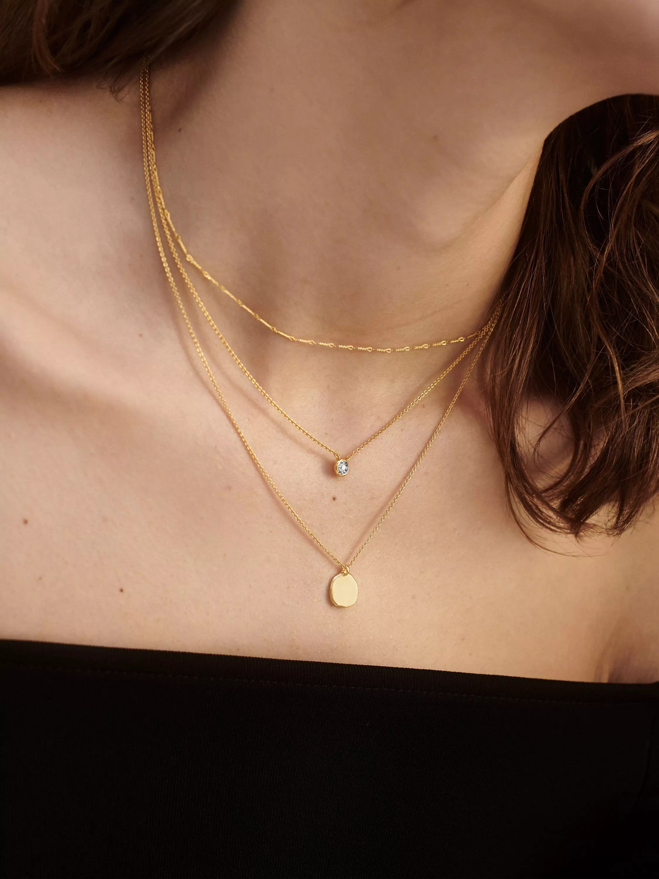 Person wearing 3 gold necklaces