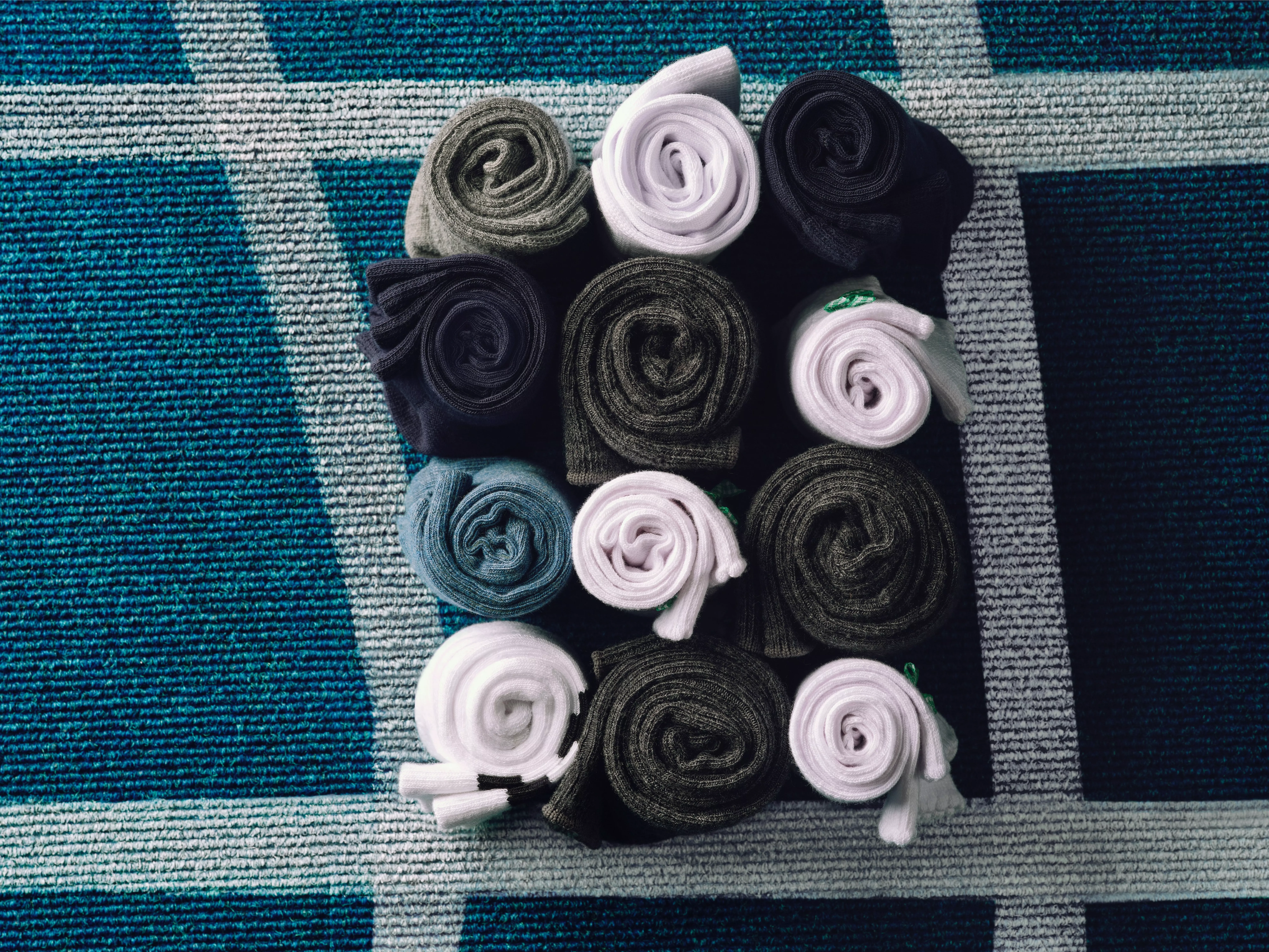 Rolled socks in assorted colours neatly packed in a suitcase on a blue and white patterned travel blanket