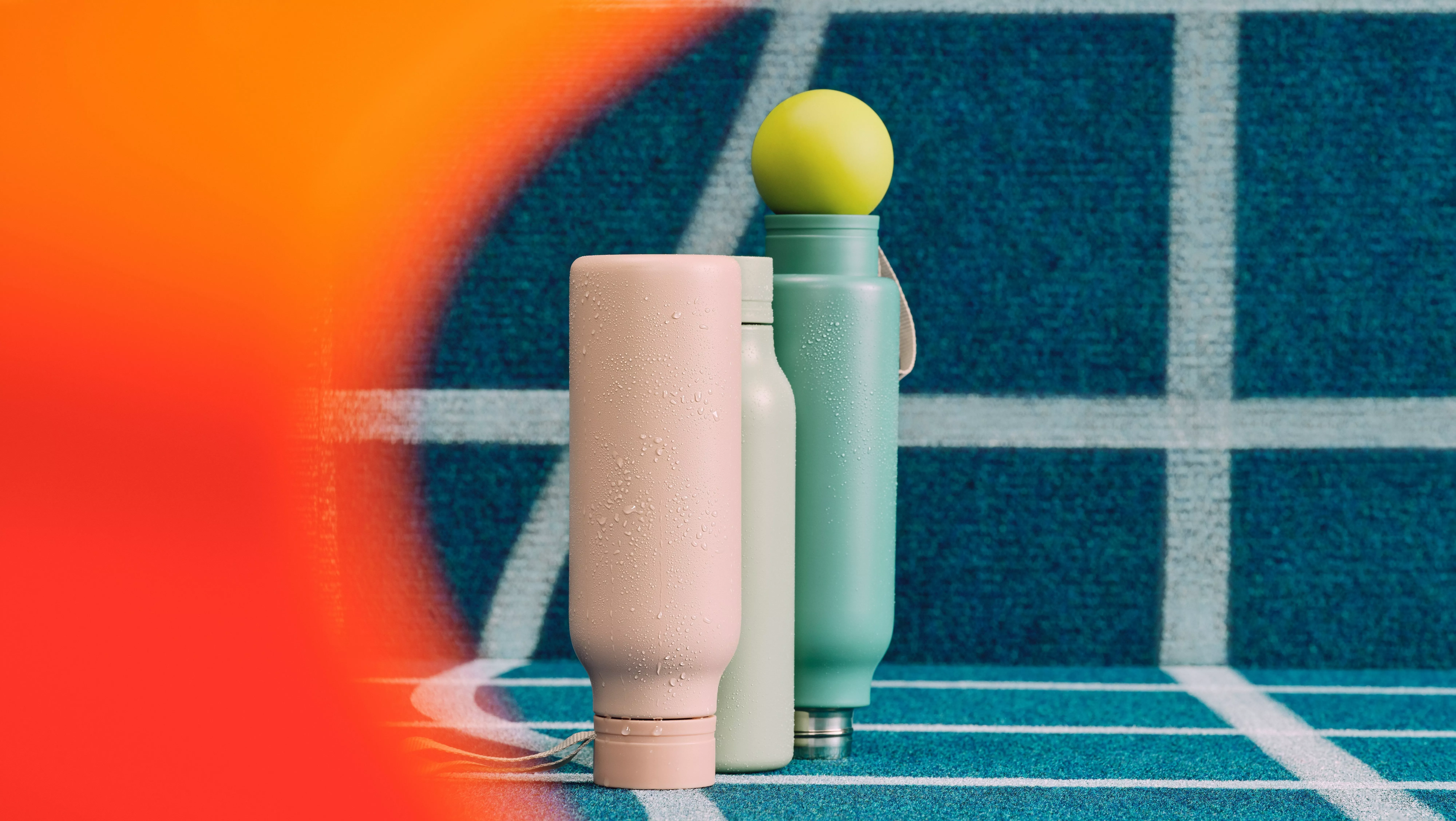 Reusable water bottles with condensation on a tennis court, beside a tennis ball, sports hydration concept