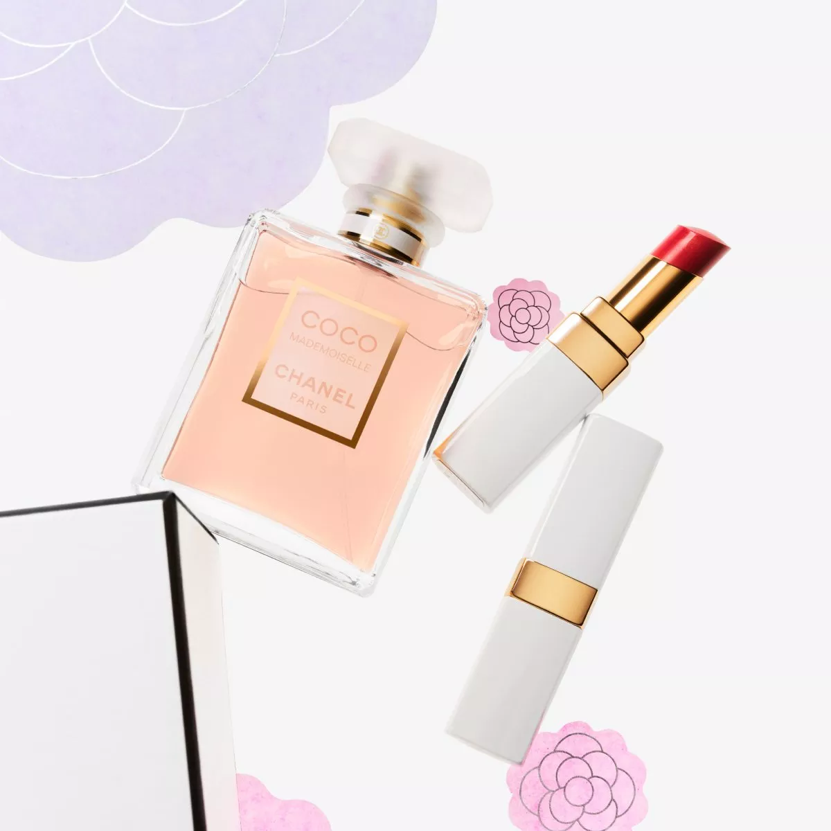 Chanel Coco Mademoiselle perfume and red lipstick on a white background with floral accents. Elegant and chic.