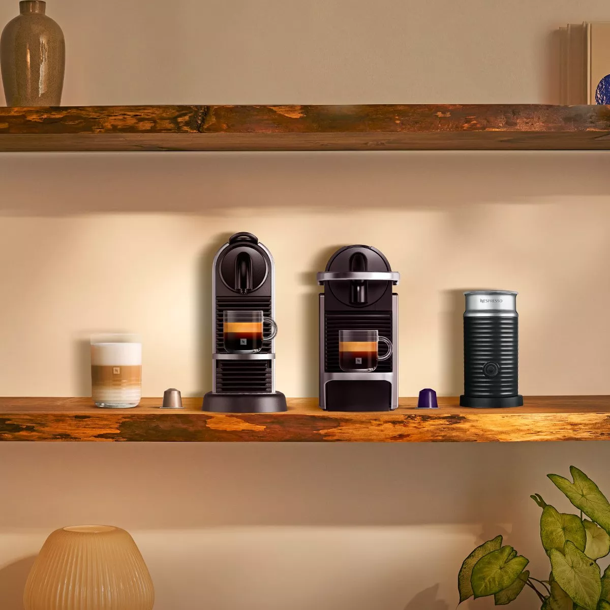 Two coffee machines with a milk frother and coffee pods next to them