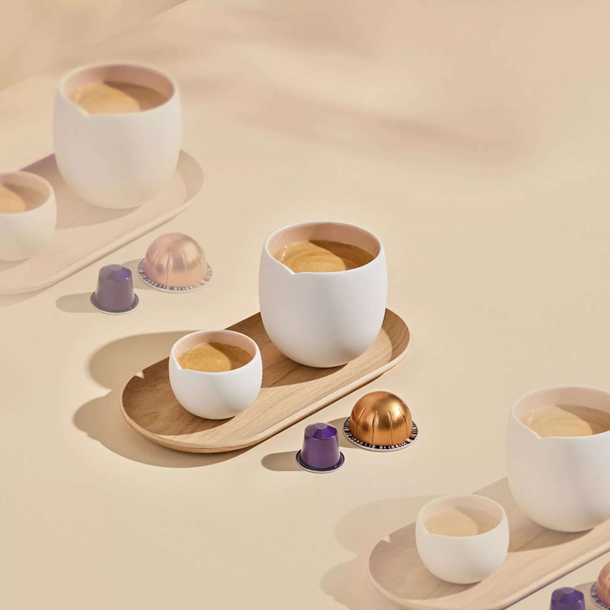 Coffee cups on a wooden tray with coffee pods scattered next to it