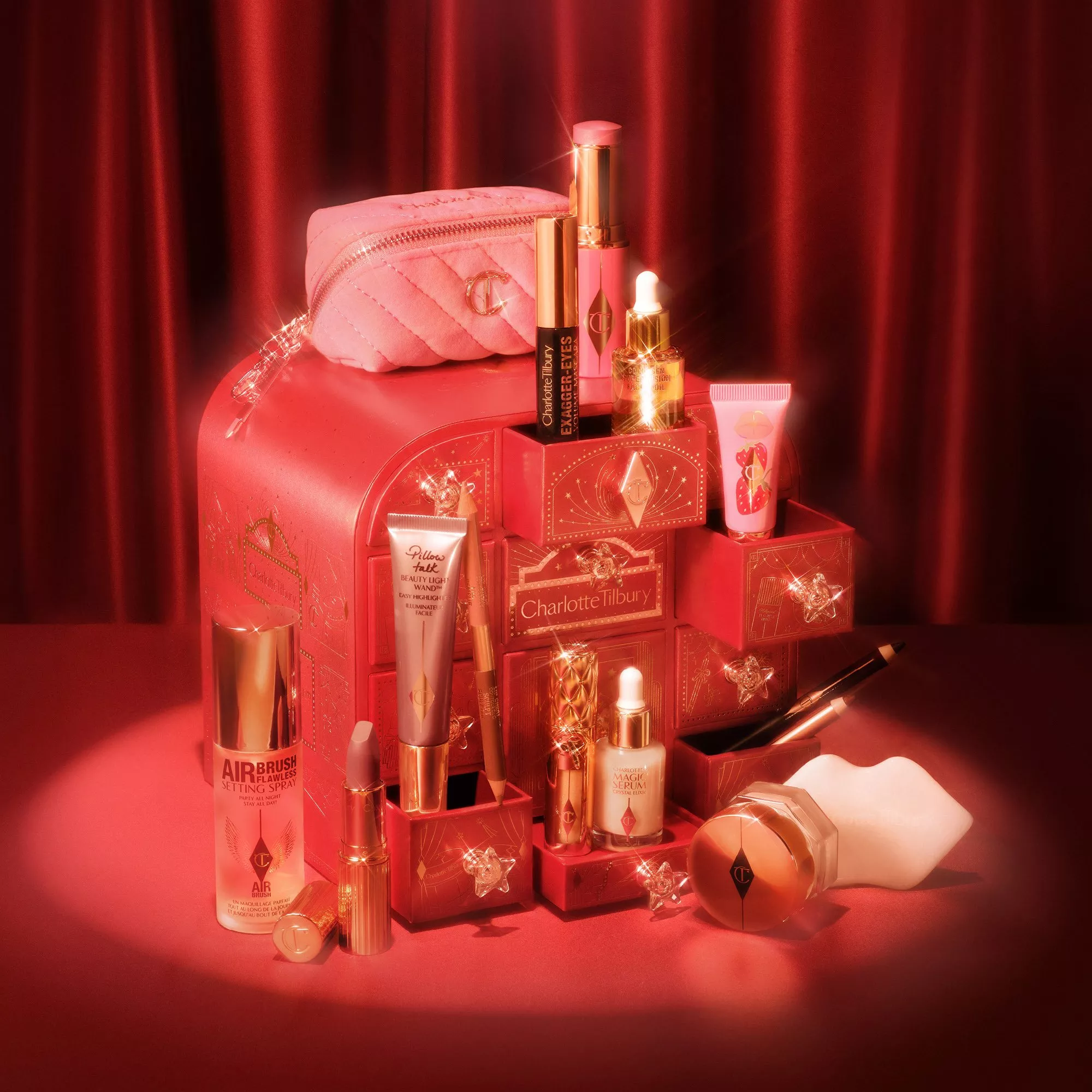 Charlotte Tilbury beauty gift set with makeup and skincare products on red vanity case backdrop