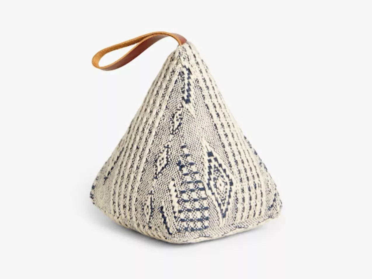 Cream and navy woven pyramid doorstop with geometric pattern and tan leather loop handle on white background