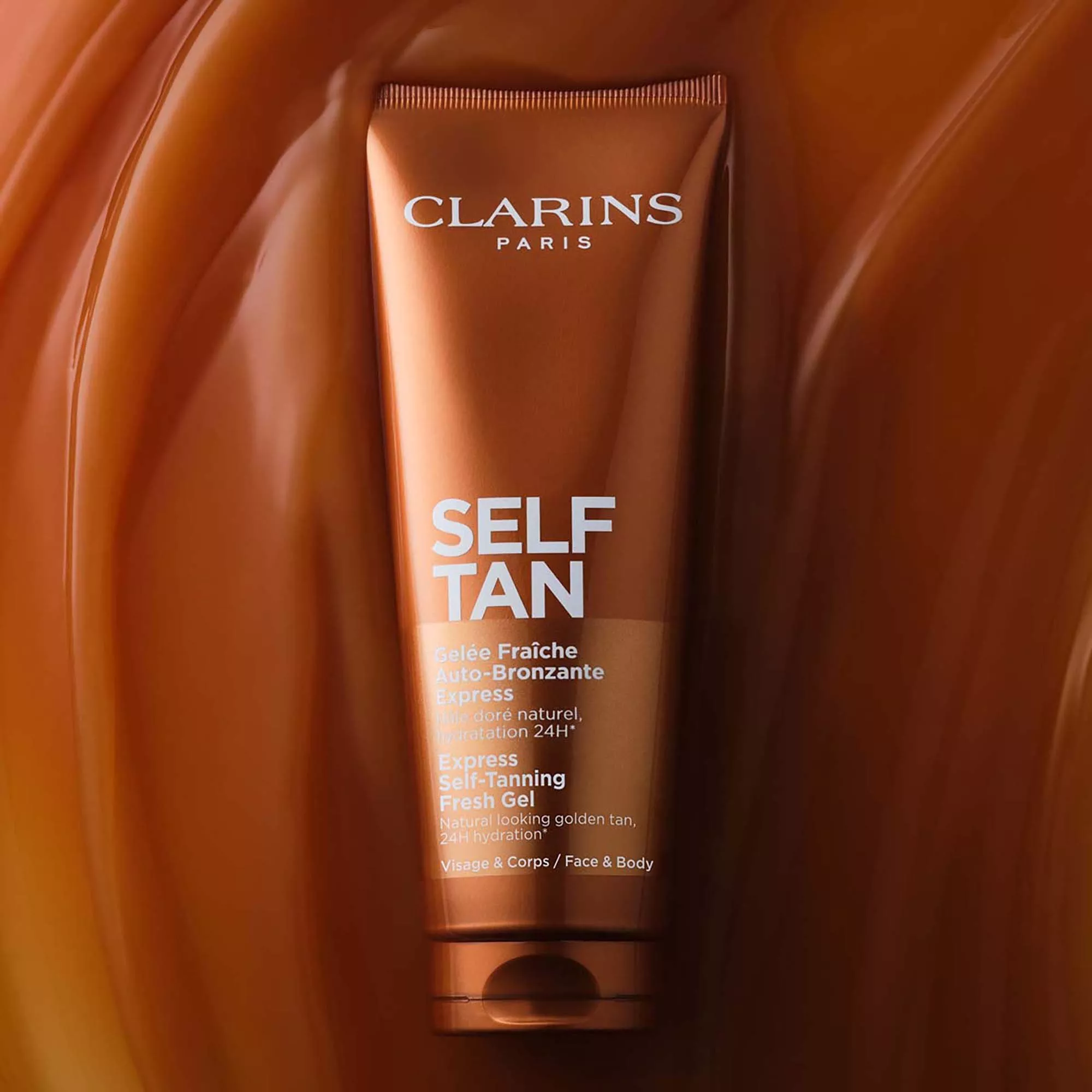 Clarins Self Tan Radiance-Plus Golden Glow Booster bottle on wet aloe vera leaves, skincare product close-up
