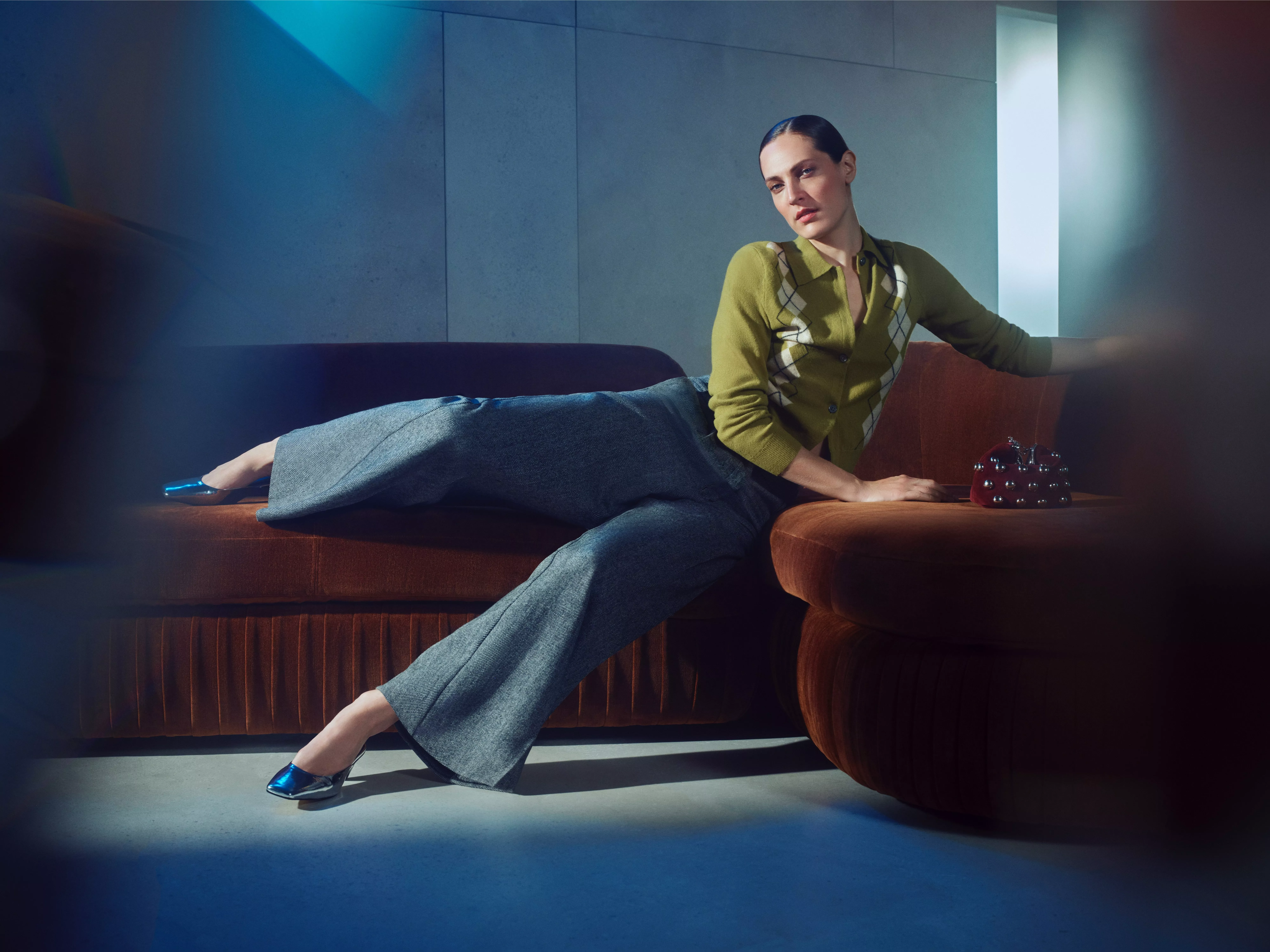 Person in a green cardigan on a red velvet sofa