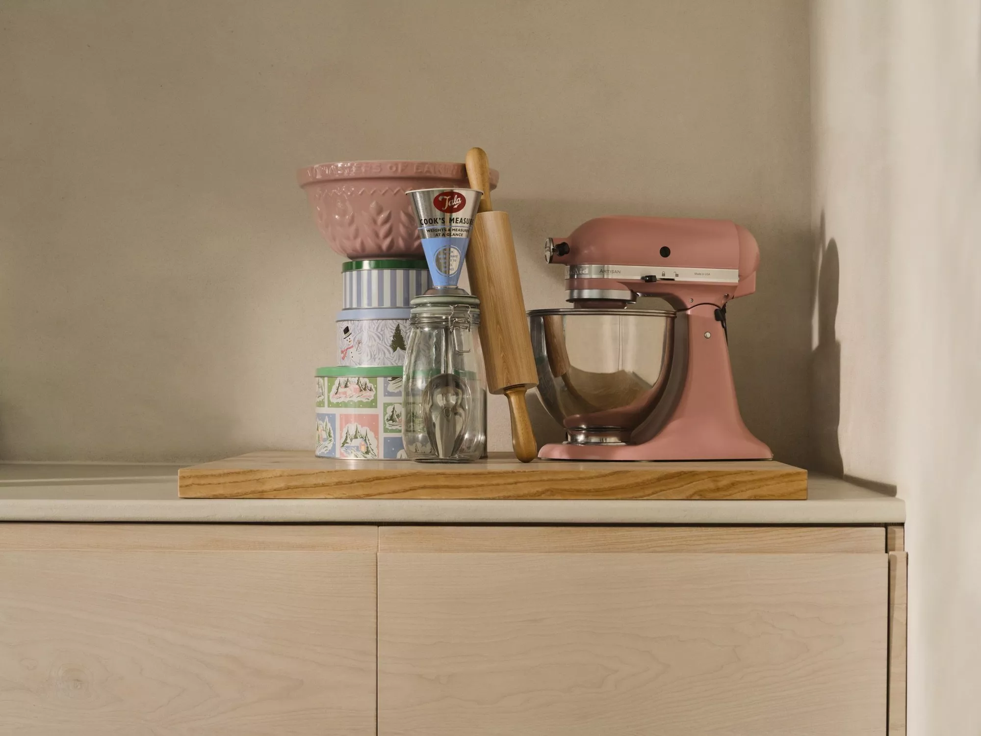 Pink baking mixer on a shelf with Christmas storage tins, rolling pin and pink mixing bowl