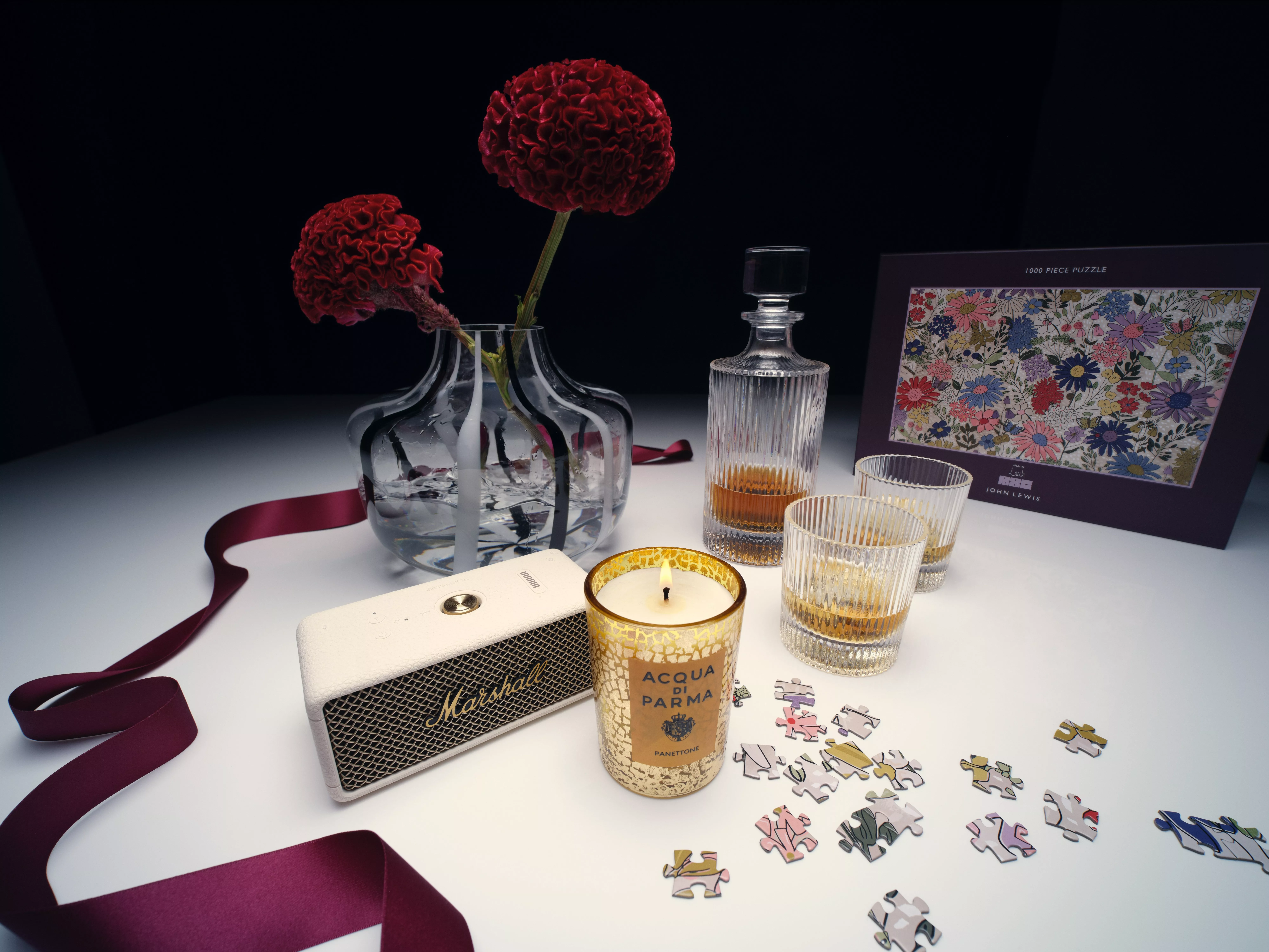 A speaker, candle, vase with carnations and jigsaw