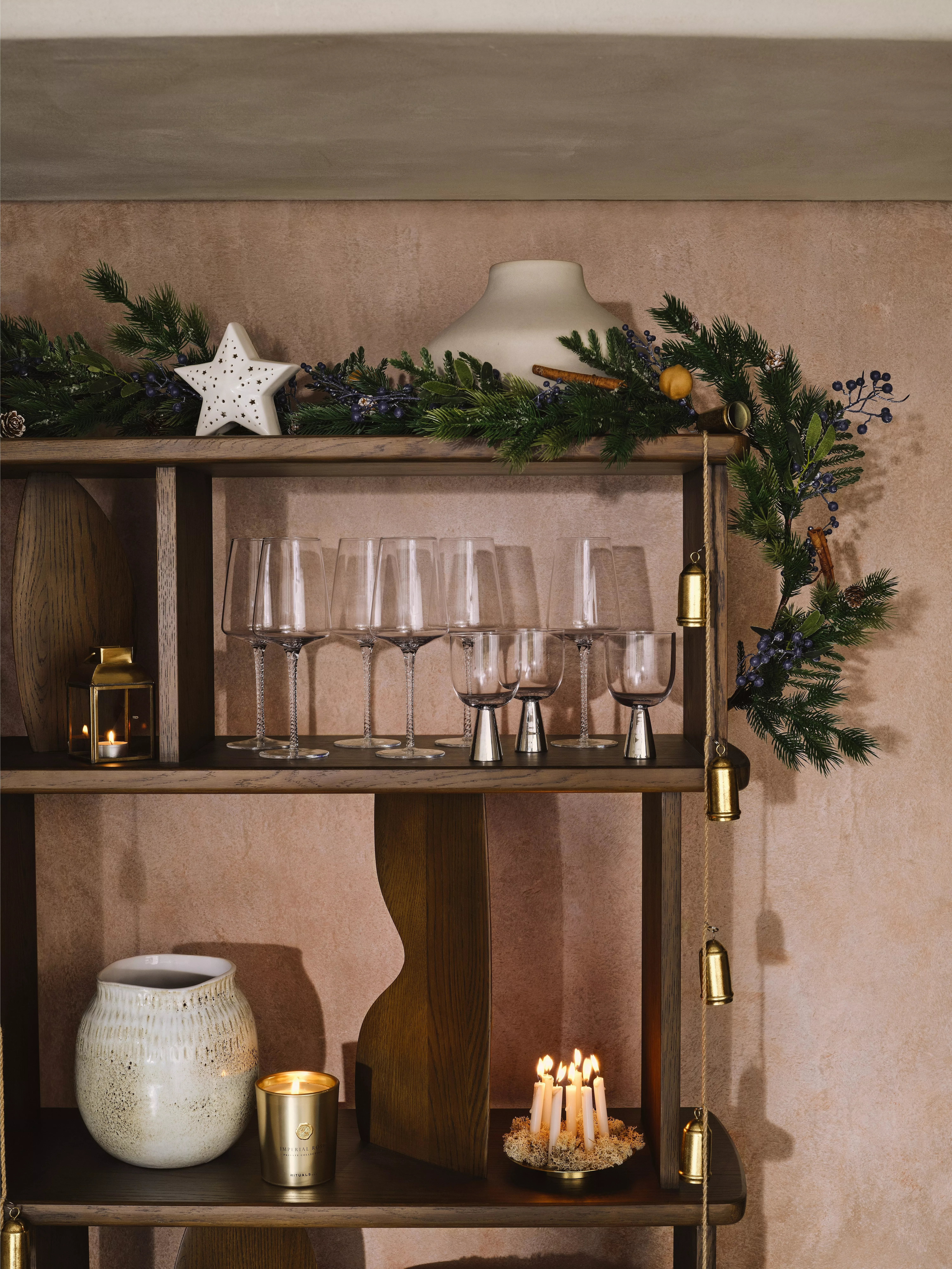 Shelving unit with Christmas garland on the top, drinking glasses and candles
