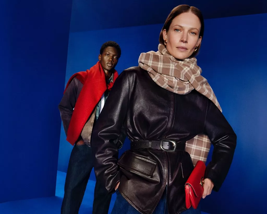 Fashion campaign with models in leather jacket and checked scarf, red clutch and scarf, studio blue backdrop