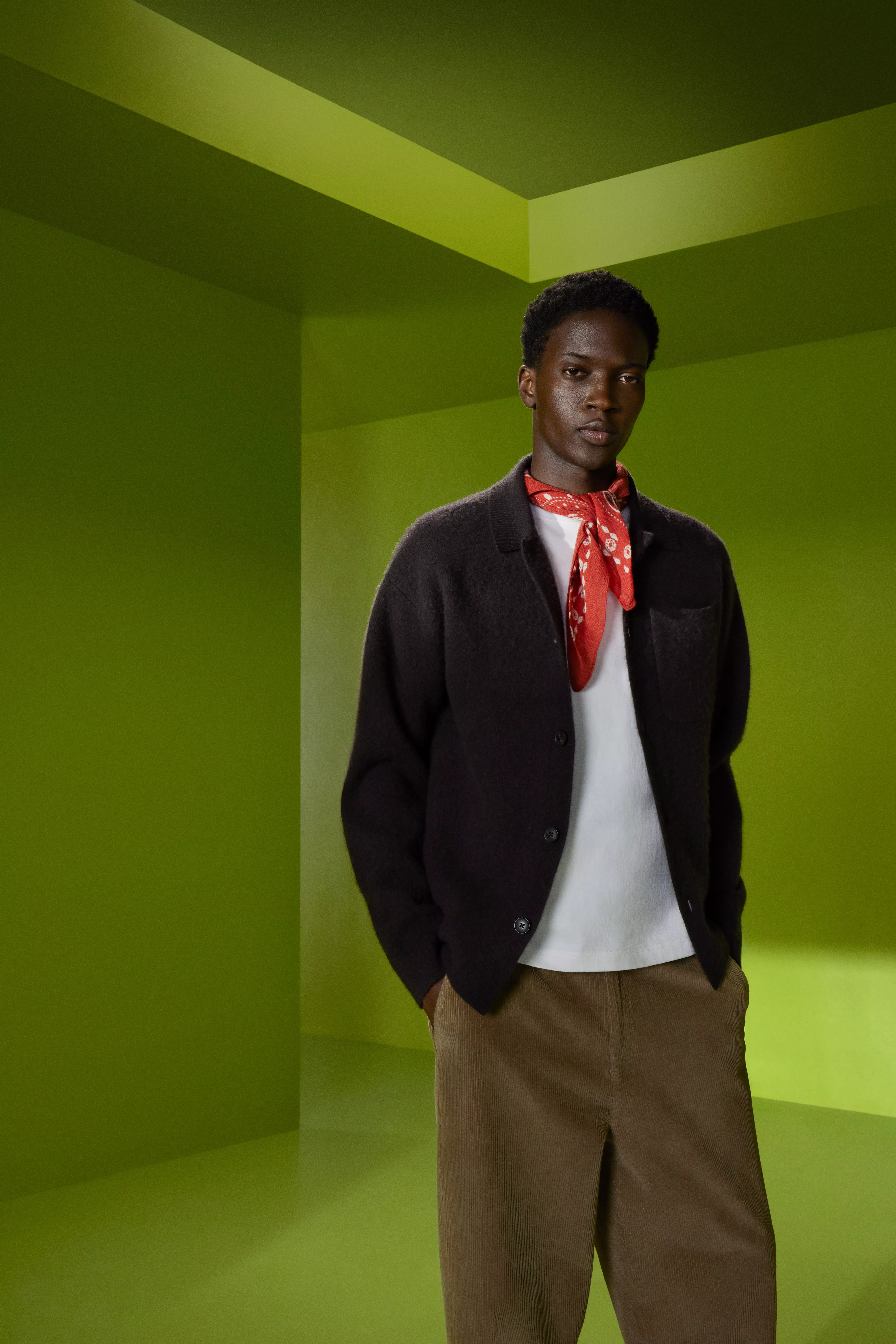 Man wearing a white t-shirt with a navy cardigan and a red scarf