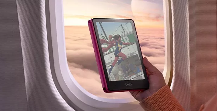 Hand holding a Kindle e-reader on a plane, reading comic book art with clouds and sunrise outside window
