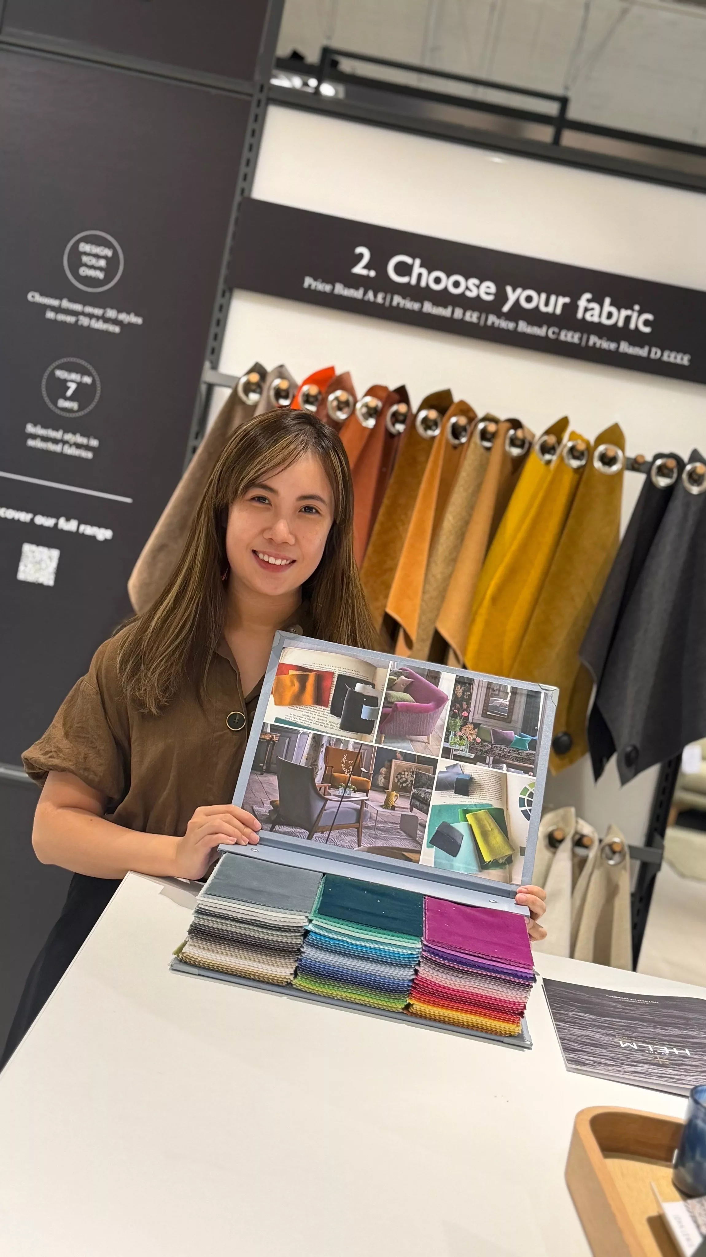 Interior designer presenting upholstery fabric swatches and mood board in a showroom with colour samples on display
