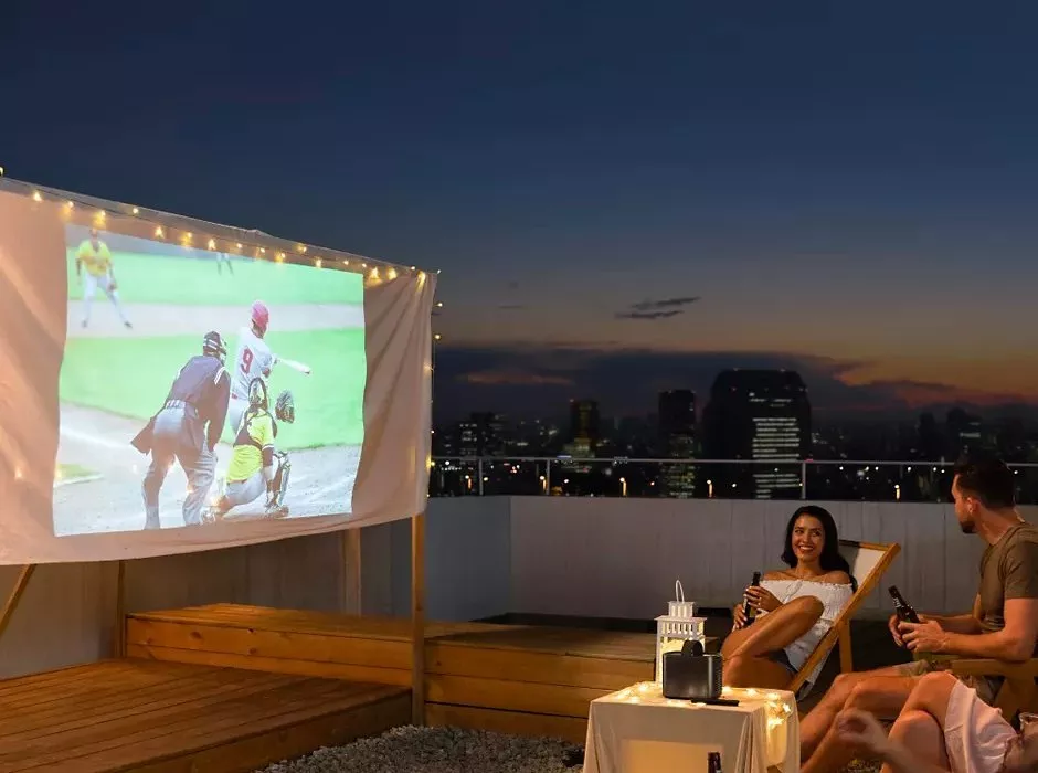 People watching a projector screen on a rooftop