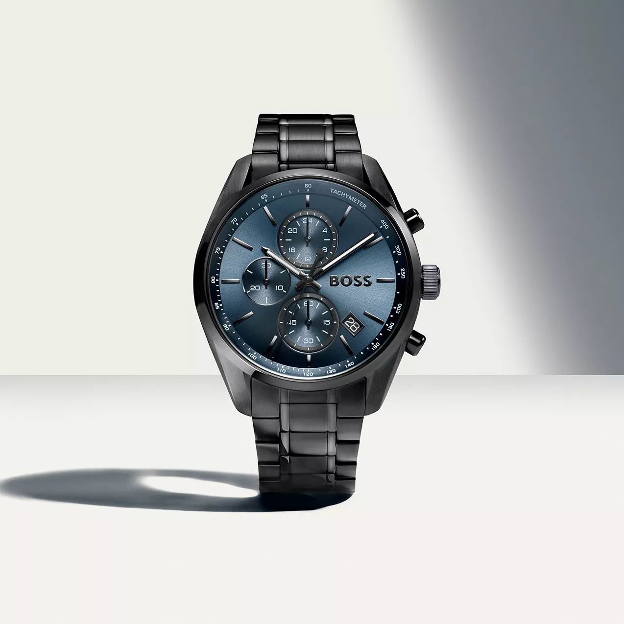 Dark grey metallic BOSS chronograph watch featuring a blue dial, sub-dials, and matching steel link bracelet.