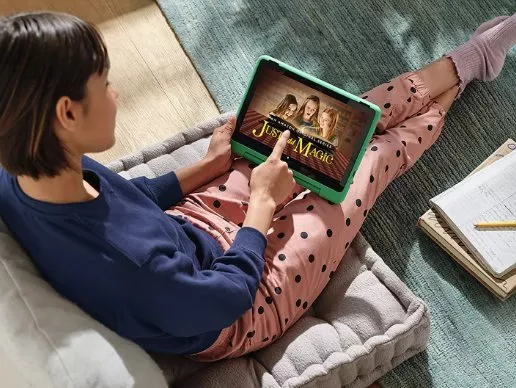 Girl lounging on beanbag using tablet at home, streaming family film, cosy living room with notebook nearby