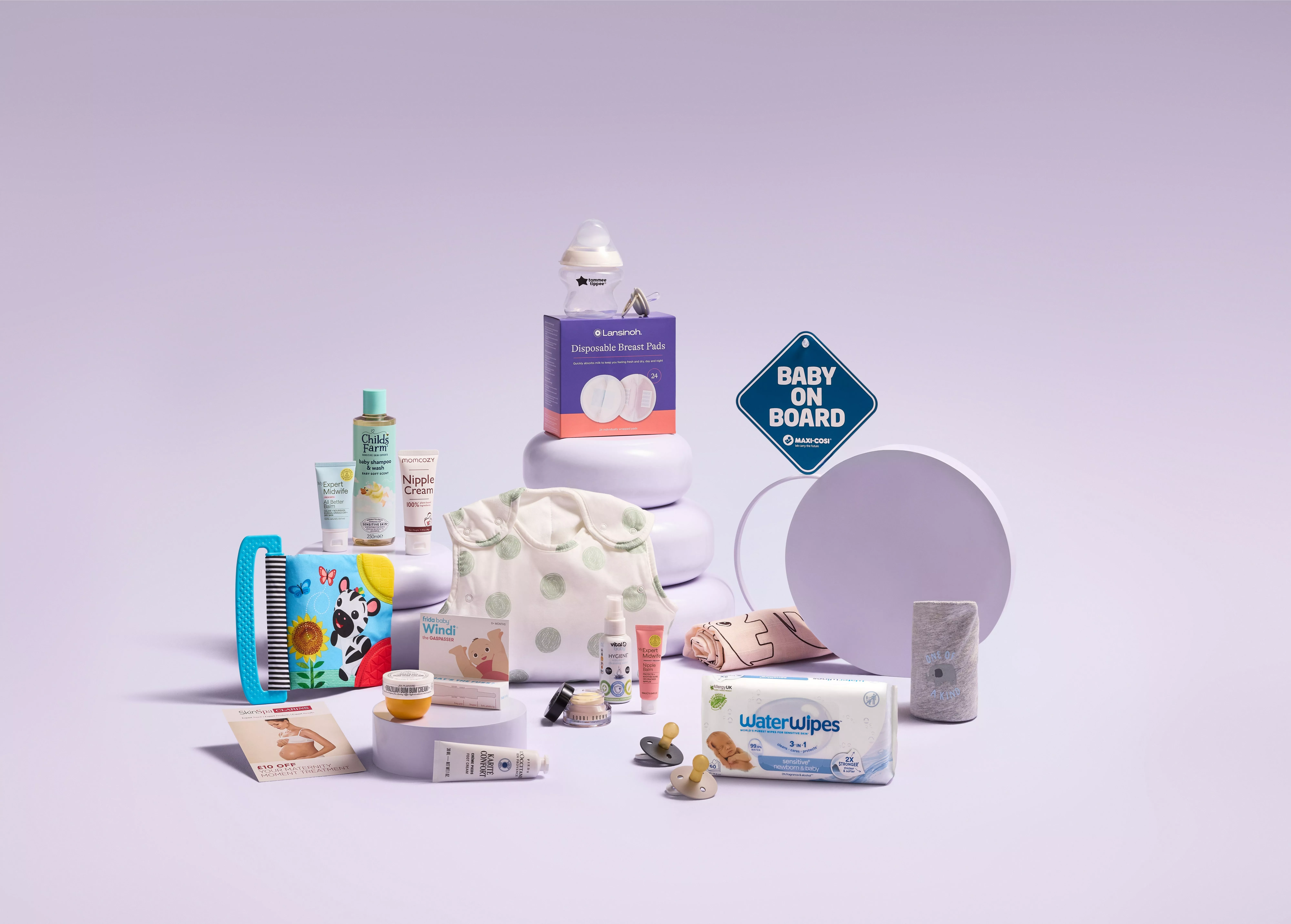 A collection of newborn essentials arranged on light purple platforms against a lilac background.