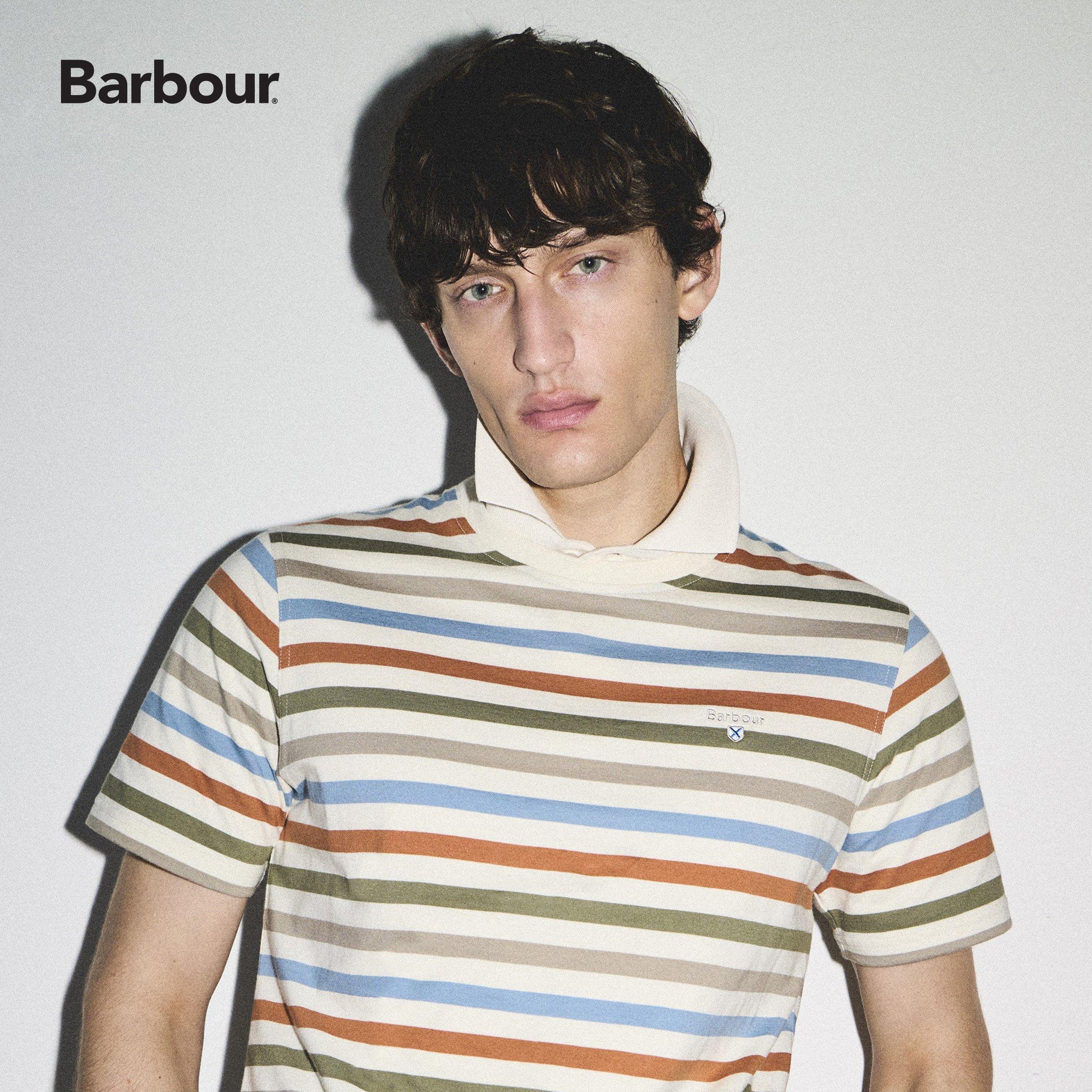 A young man with dark, wavy hair wearing a striped polo shirt, looking at the camera with a neutral expression.