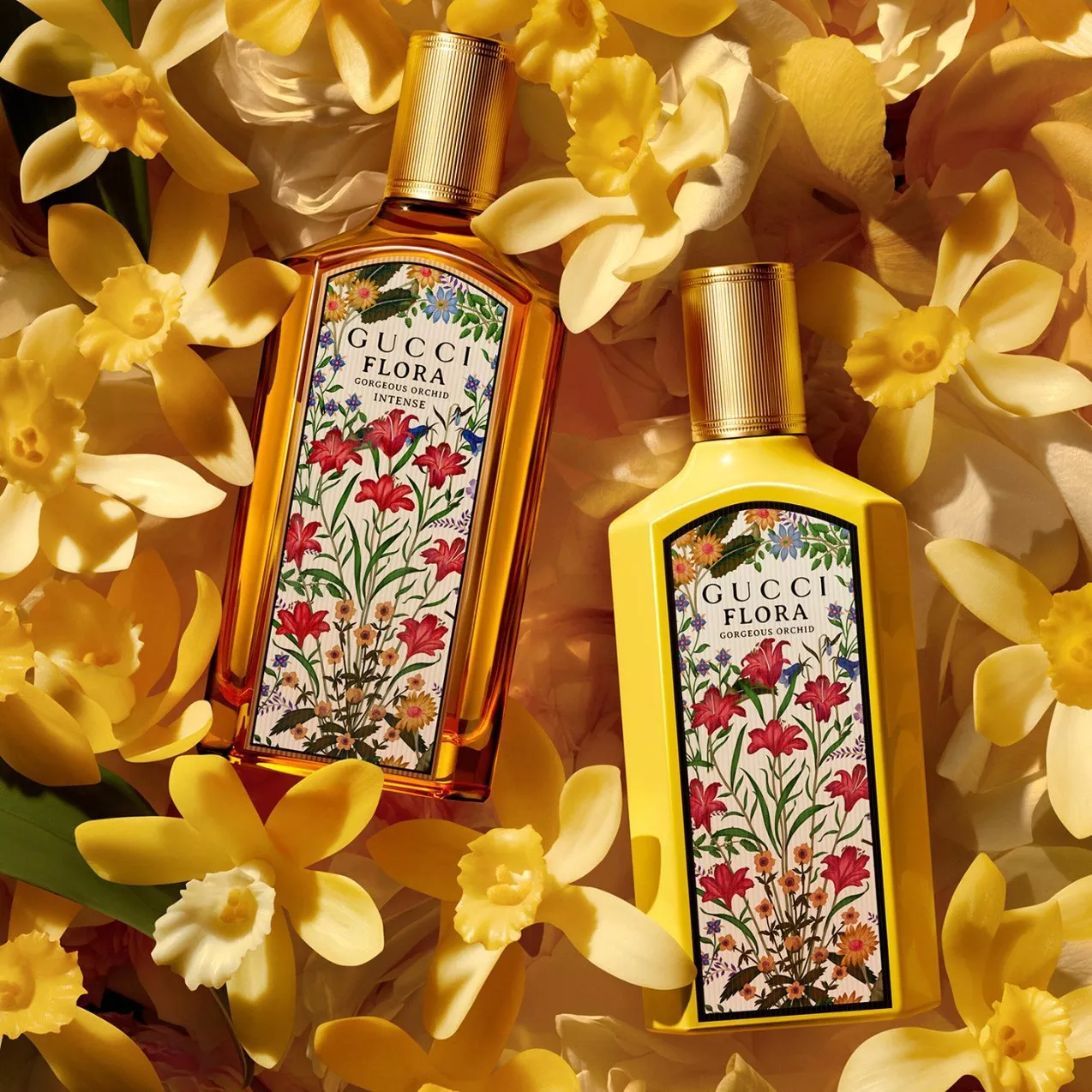 Two Gucci Flora perfume bottles—one clear glass and one opaque yellow—nestled among vibrant yellow orchid blossoms.