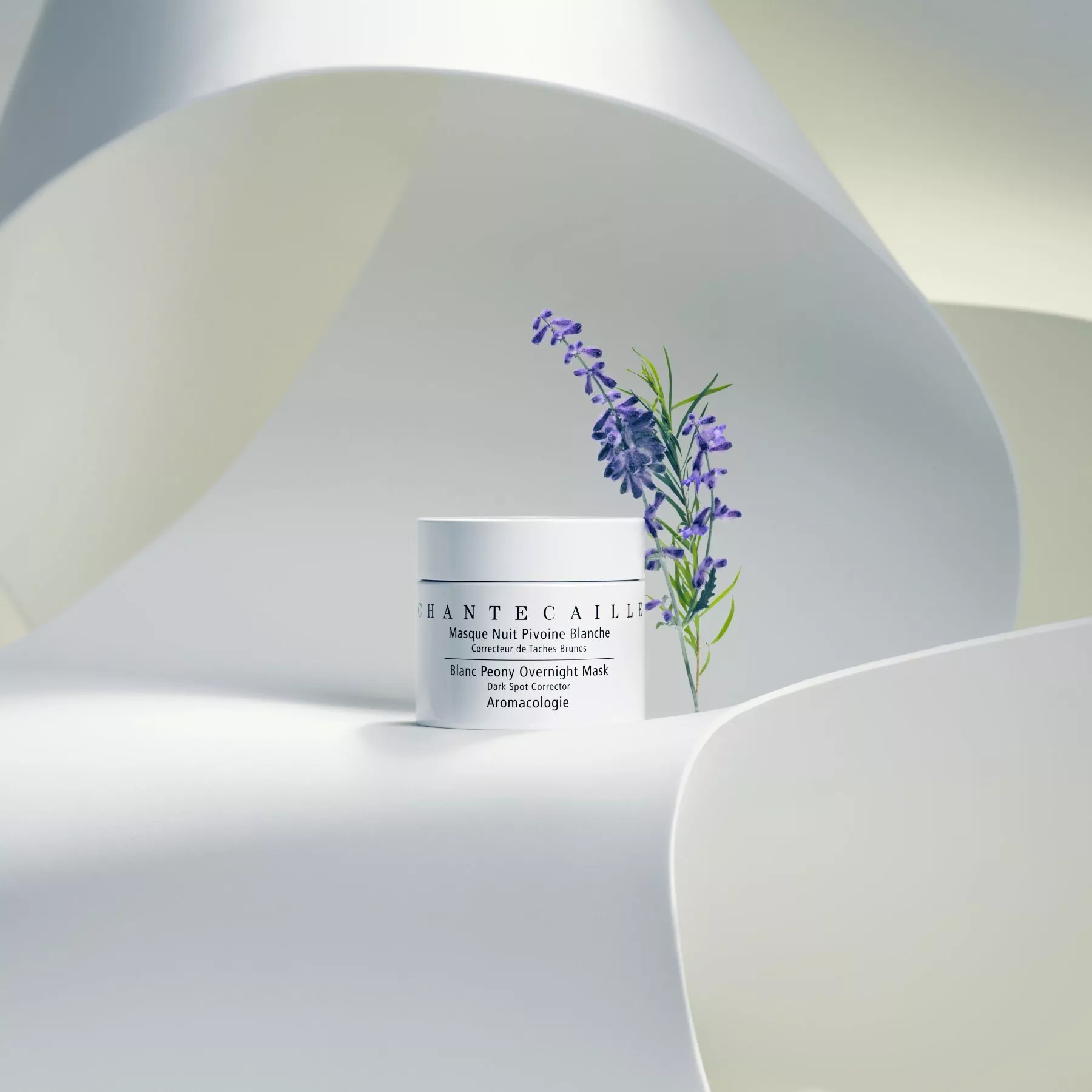 Chantecaille mask with lavender on flowing white fabric backdrop, evoking luxury skincare elegance.