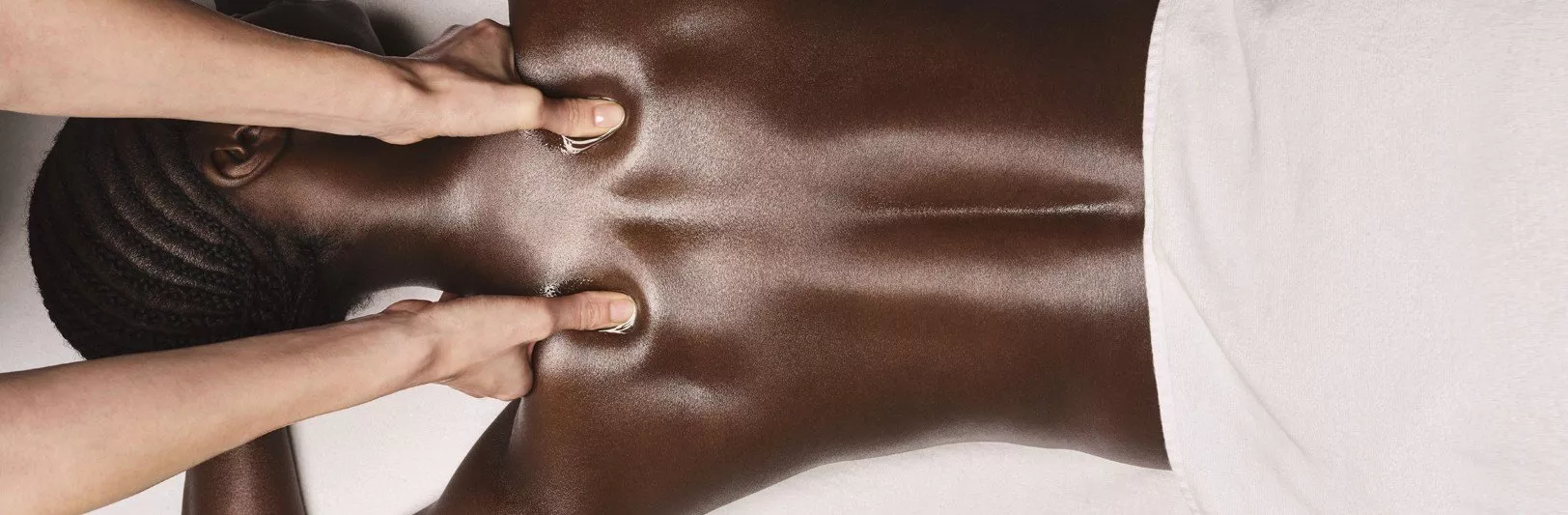 Deep tissue back massage with therapist thumbs on oiled skin, relaxing spa treatment for muscle tension