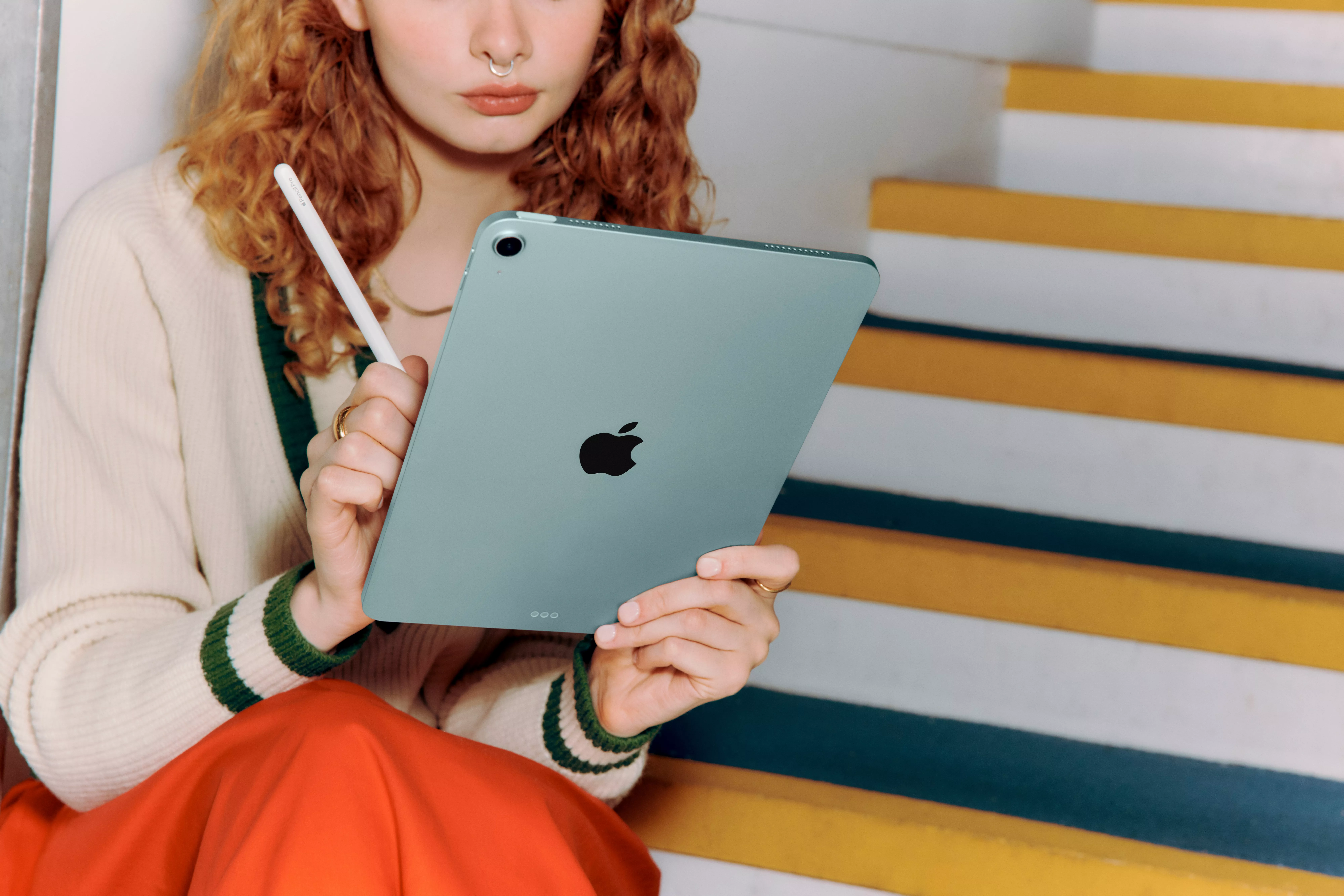 Three individuals are gathered around a blue laptop, sitting on a sofa, engaged in conversation.