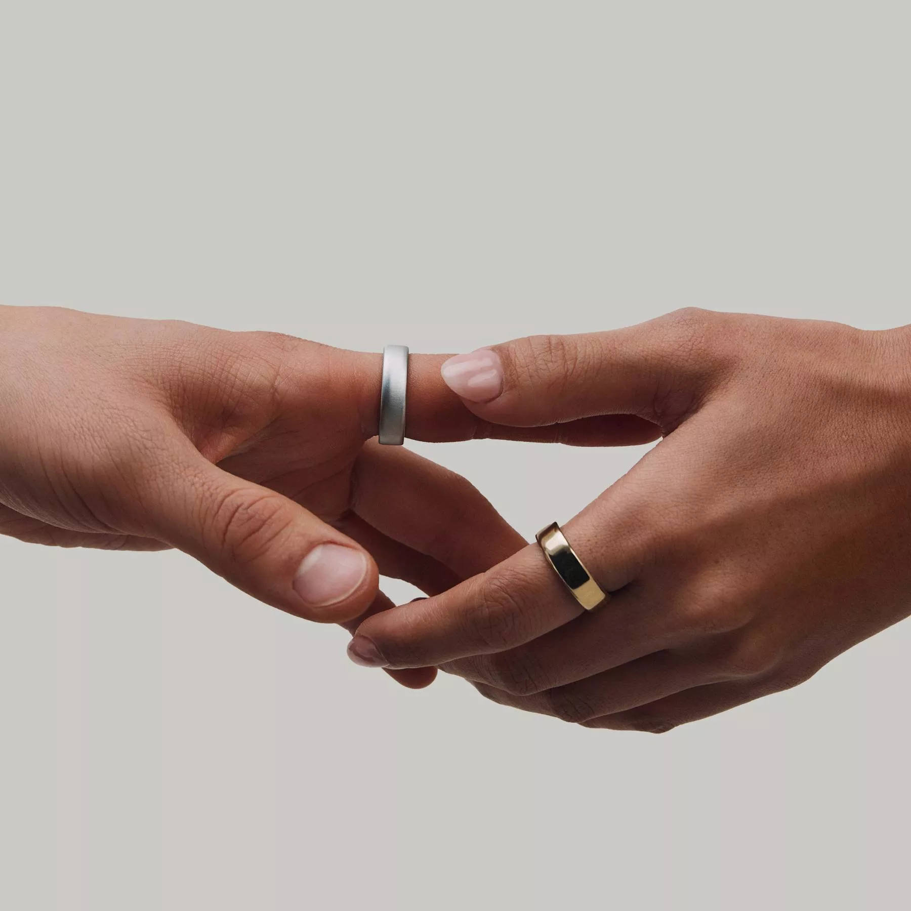 Close-up of hands exchanging a silver and gold wedding ring, symbolising commitment and marriage vows