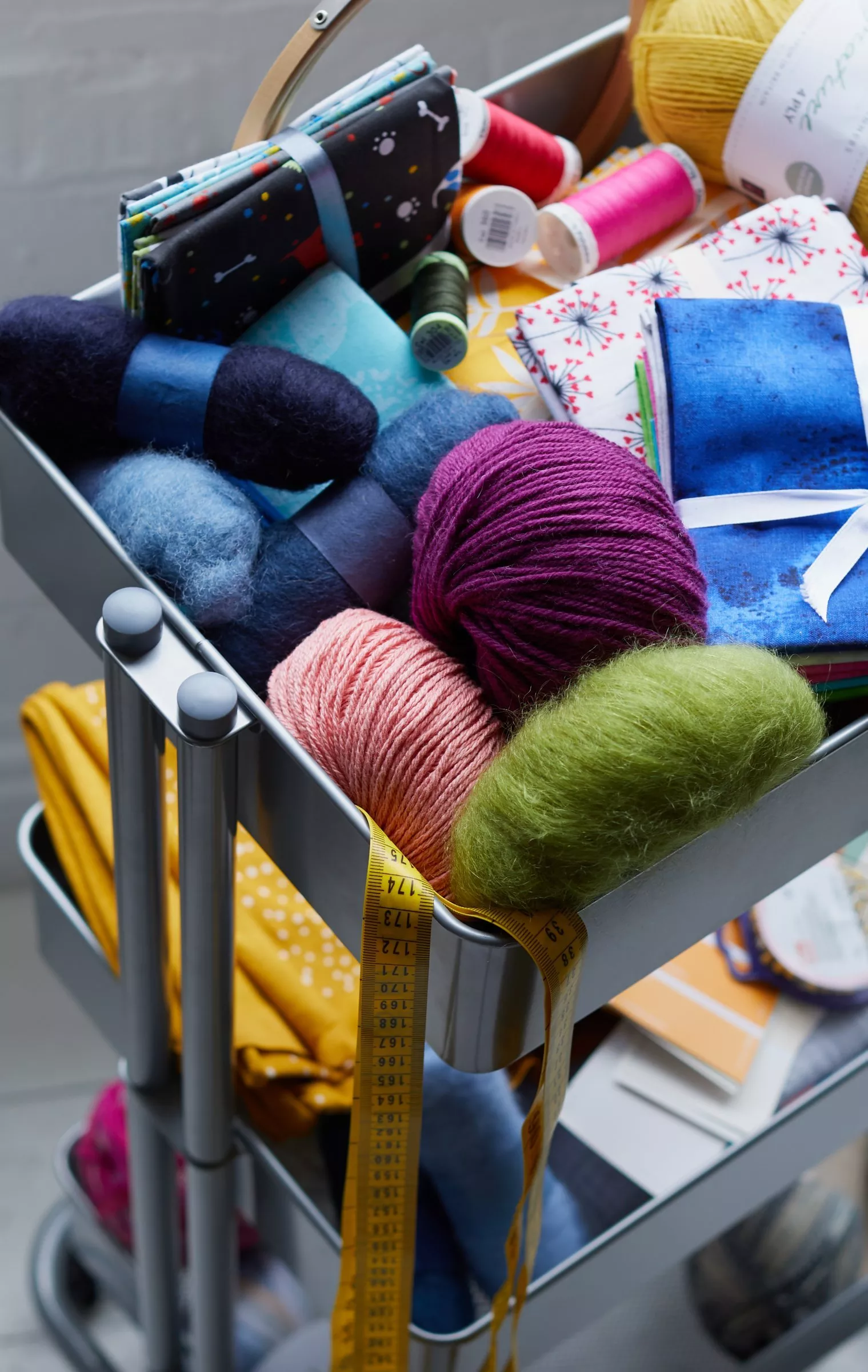 Close-up of hands doing punch needle embroidery in a hoop, creating a colourful floral textile craft pattern