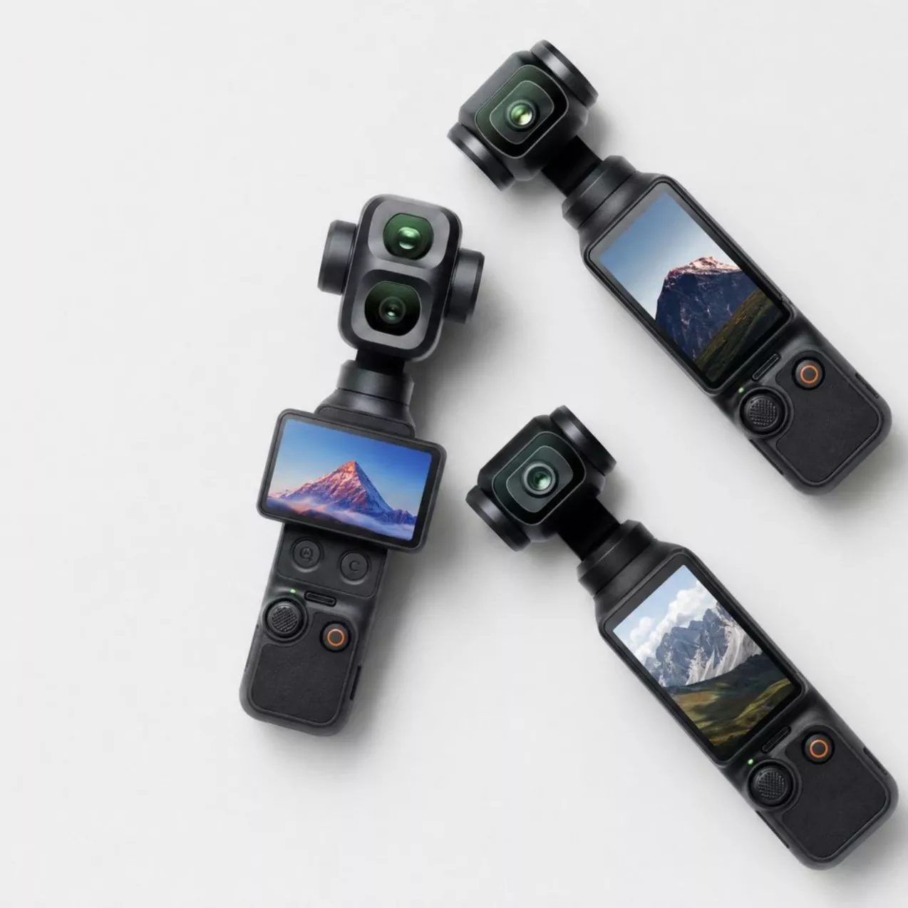 Three black handheld cameras arranged on a light background, each showing a different mountain landscape on its screen.