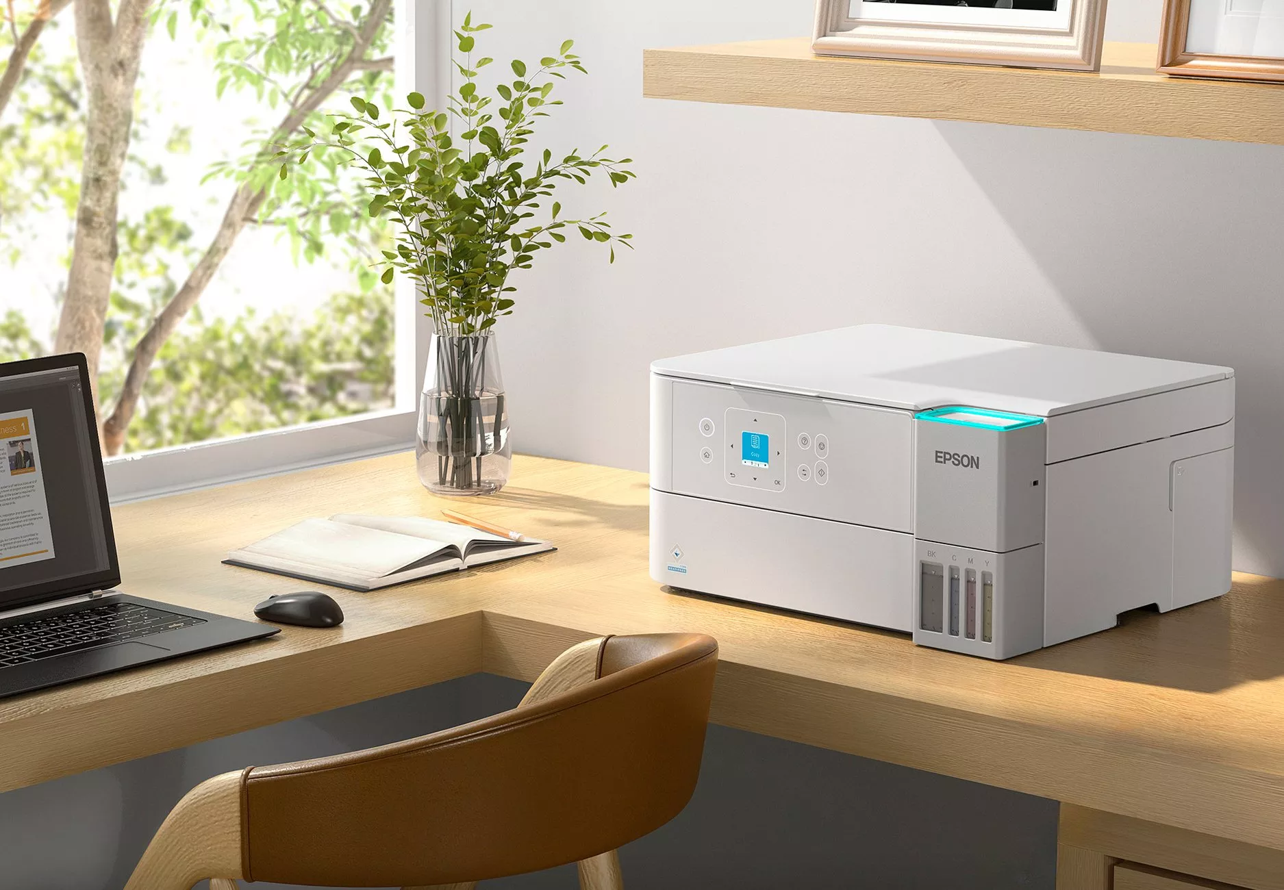 Man in orange shirt and black trousers sits on a sofa holding Epson printer ink, next to an Epson printer.