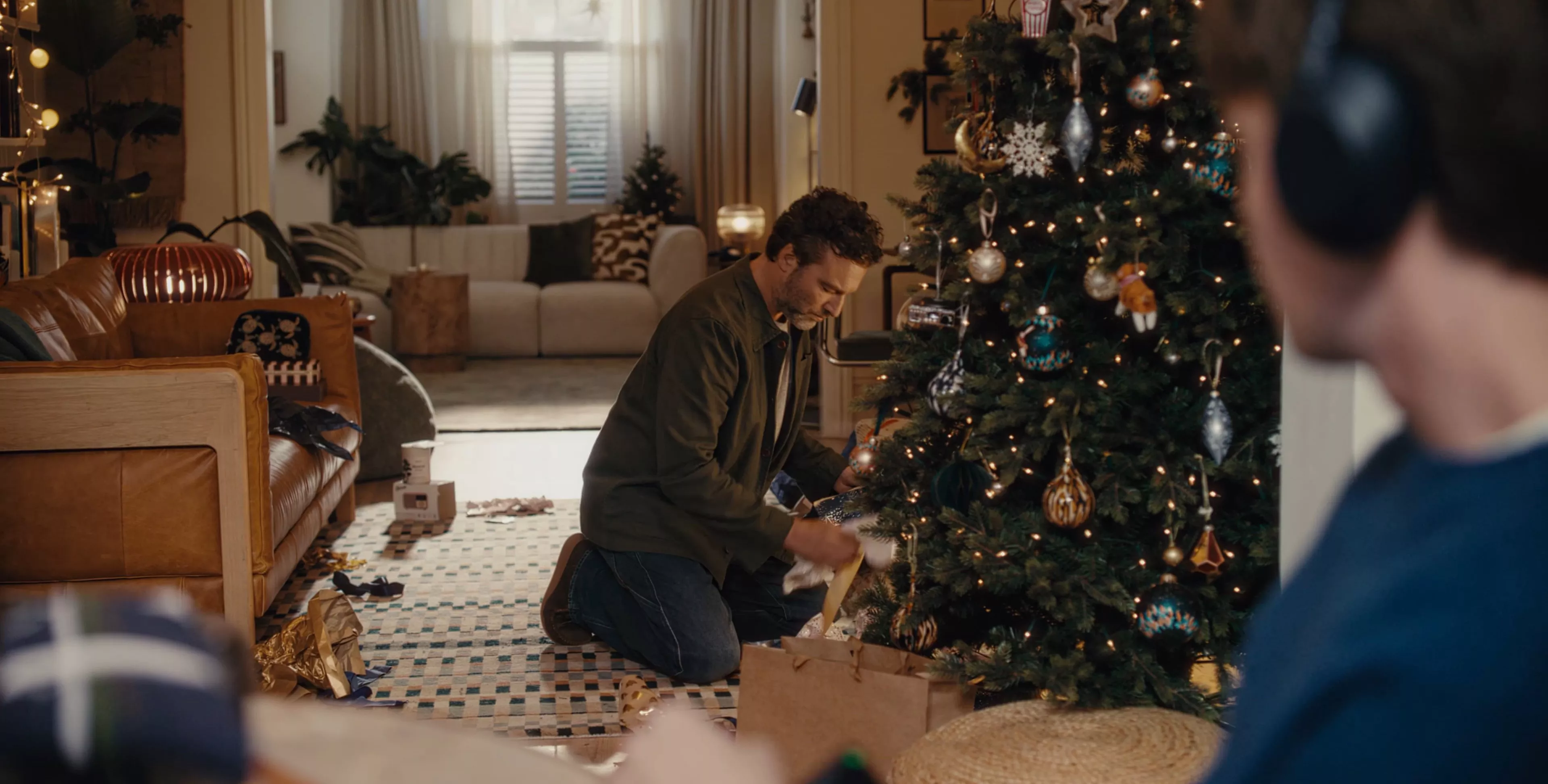 Man kneels by a Christmas tree in a living room