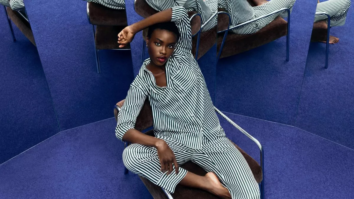 woman wearing a striped matching pyjama set sitting on a brown leather chair