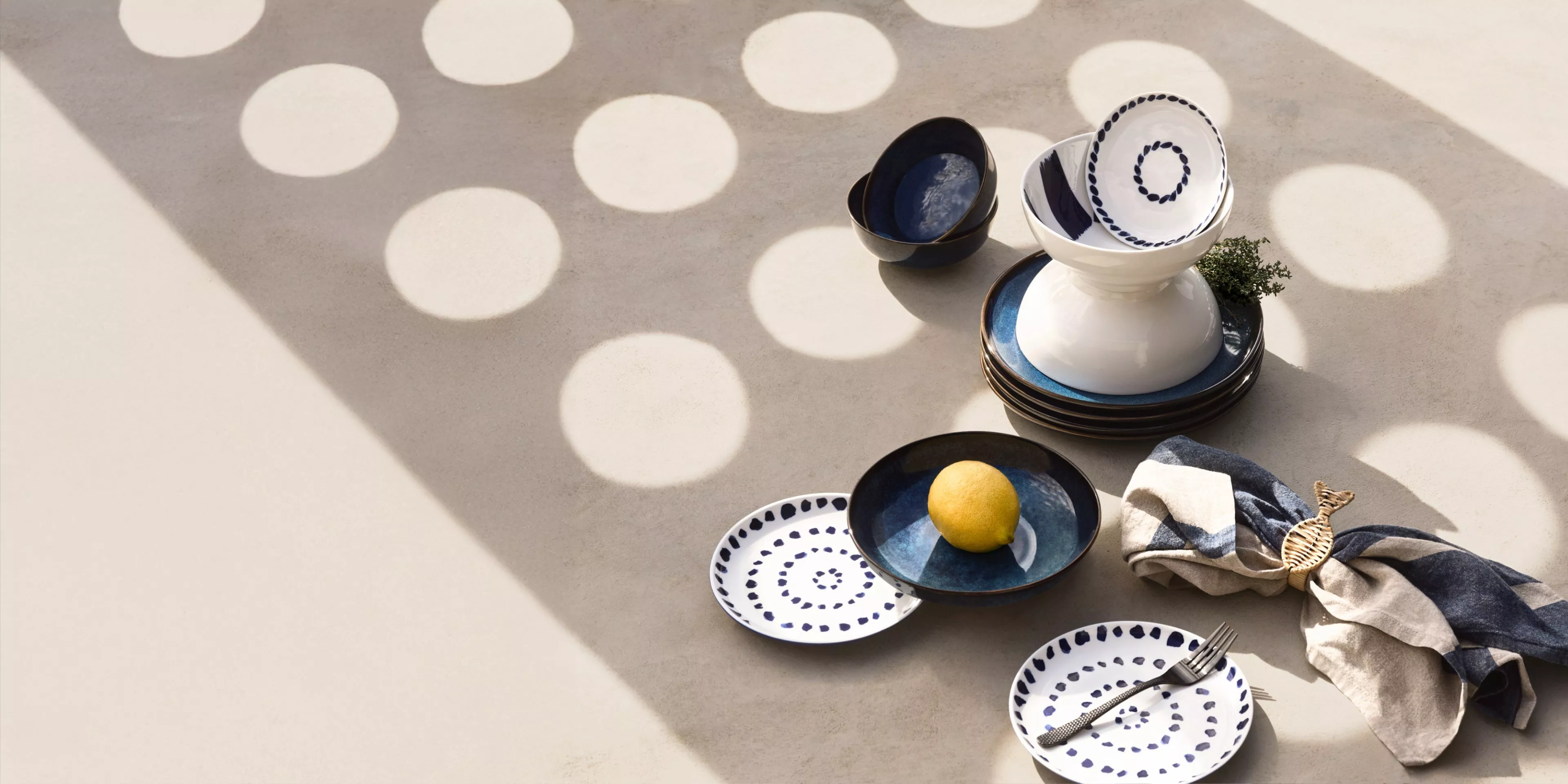 a blue and white dinning set on a sun speckled concrete table