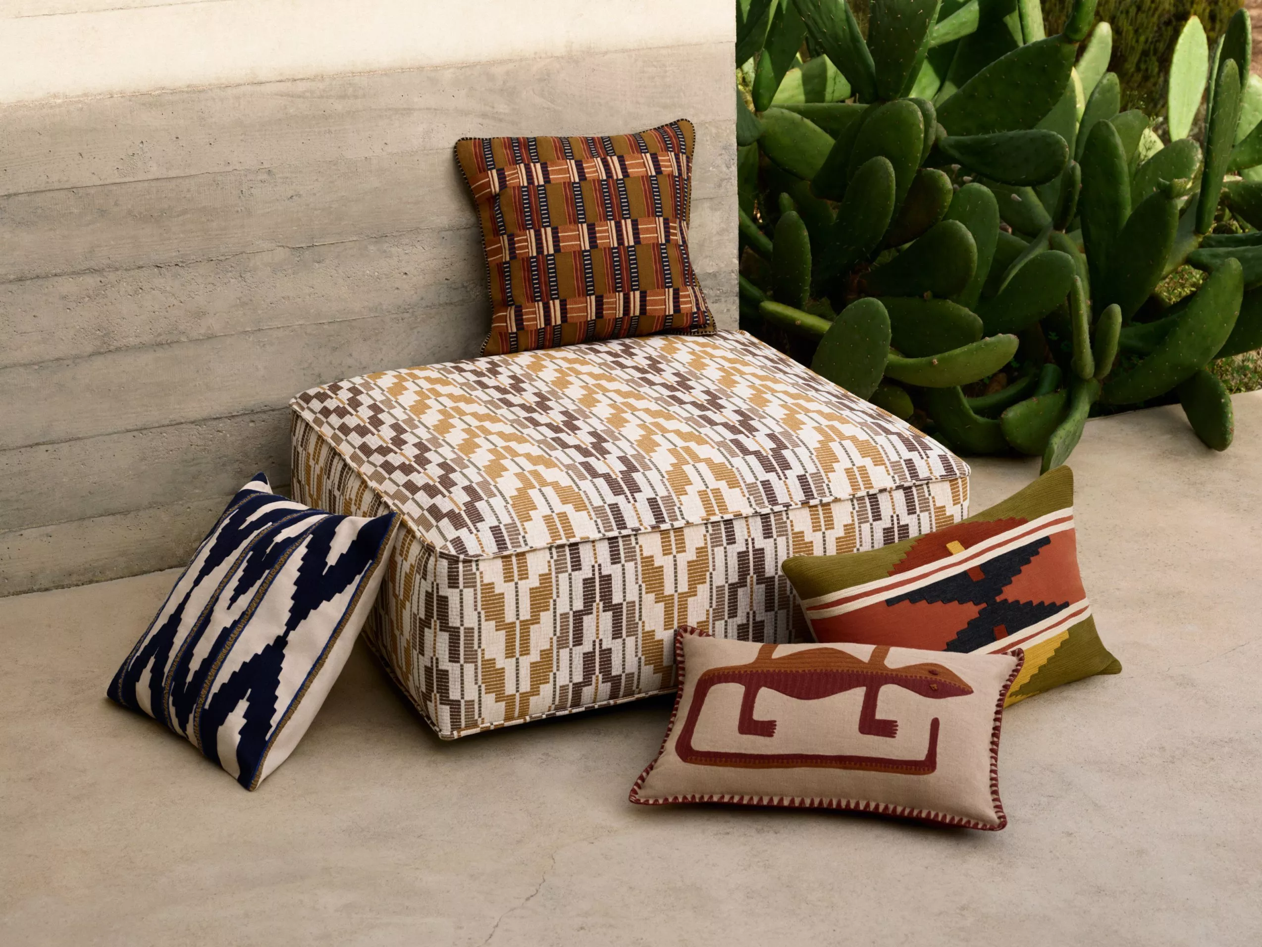 cushions on a concrete wall next to a cactus