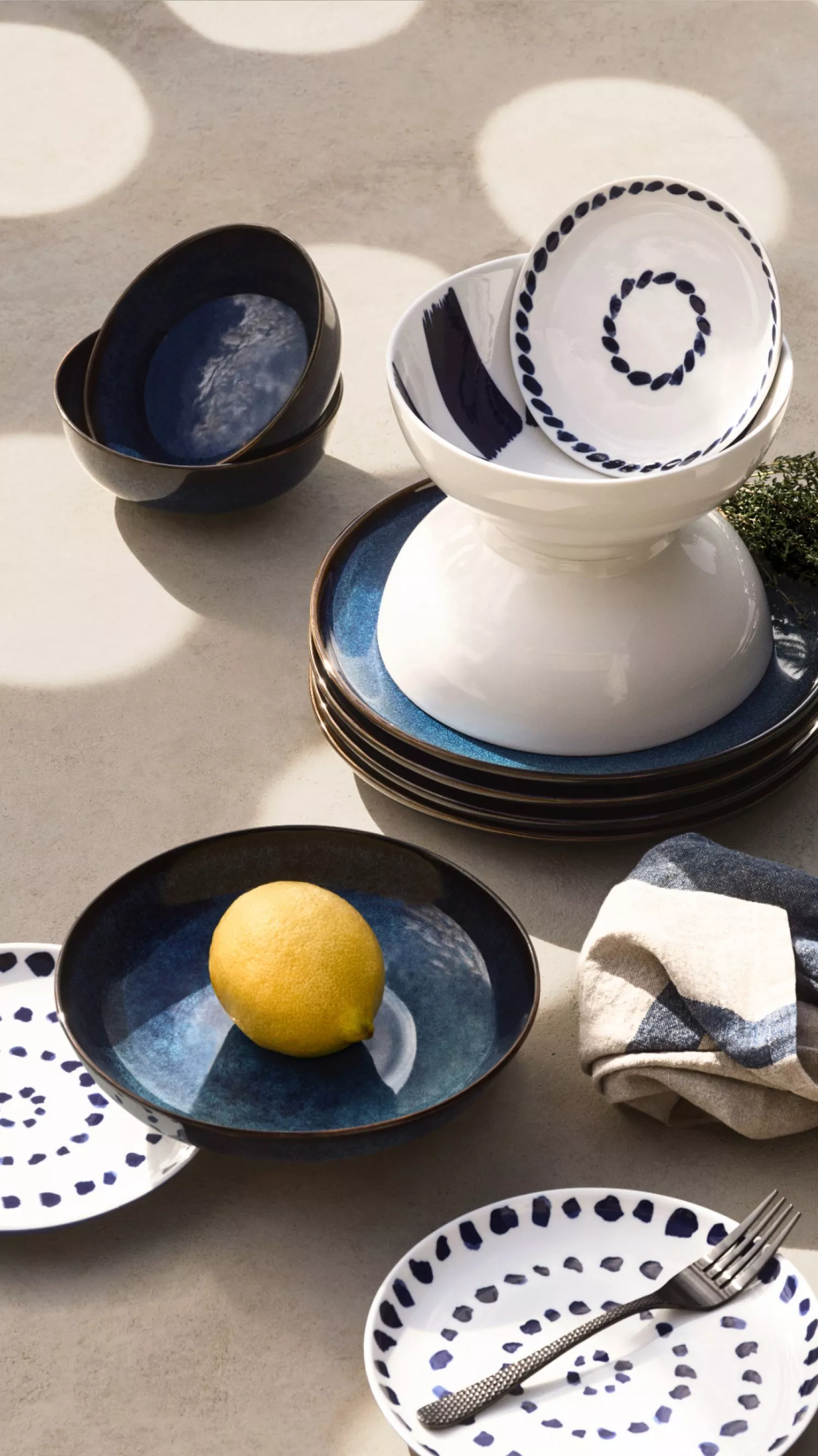 a blue and white dinning set on a sun speckled concrete table