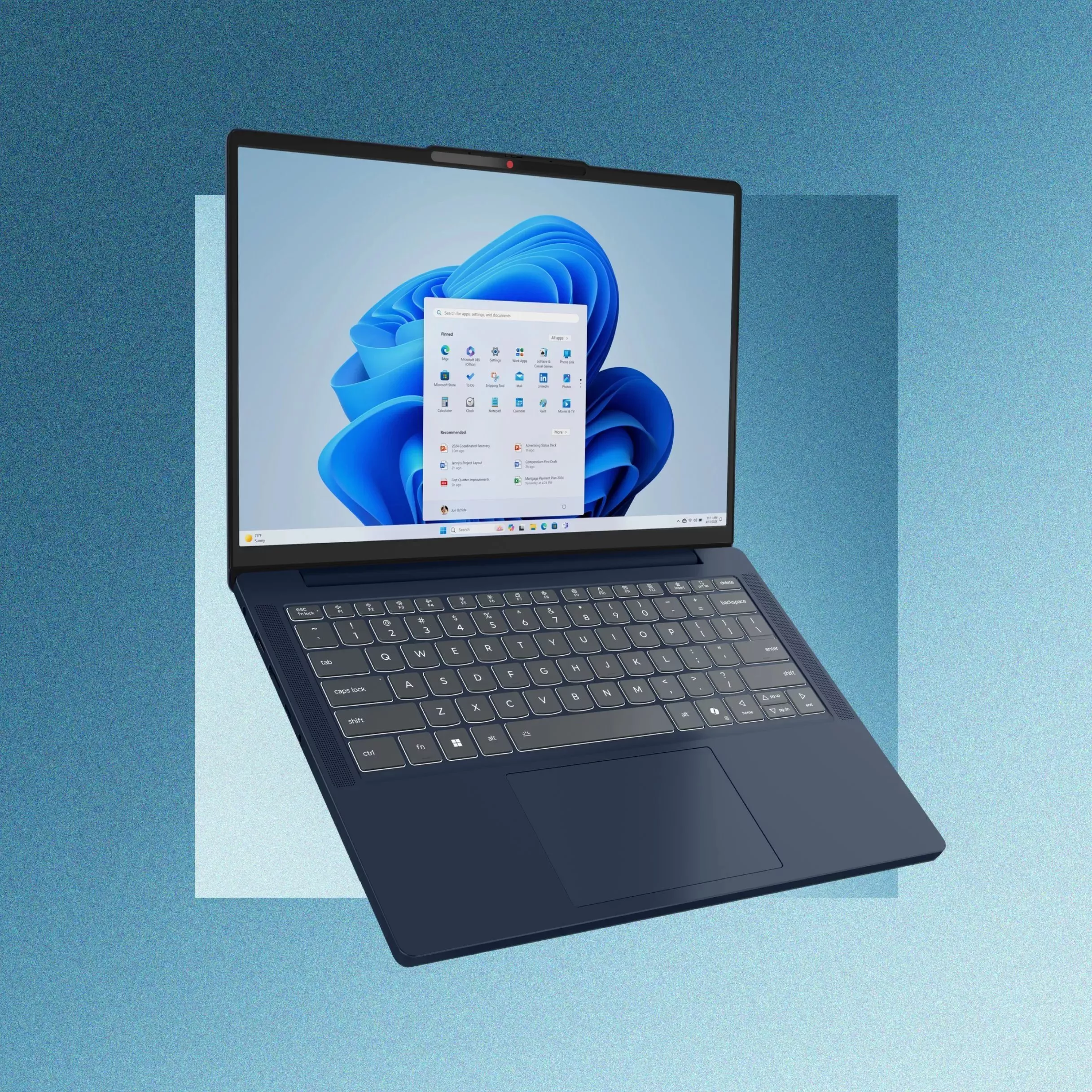 Modern laptop with Windows 11 Start menu on screen, backlit keyboard and trackpad on blue background