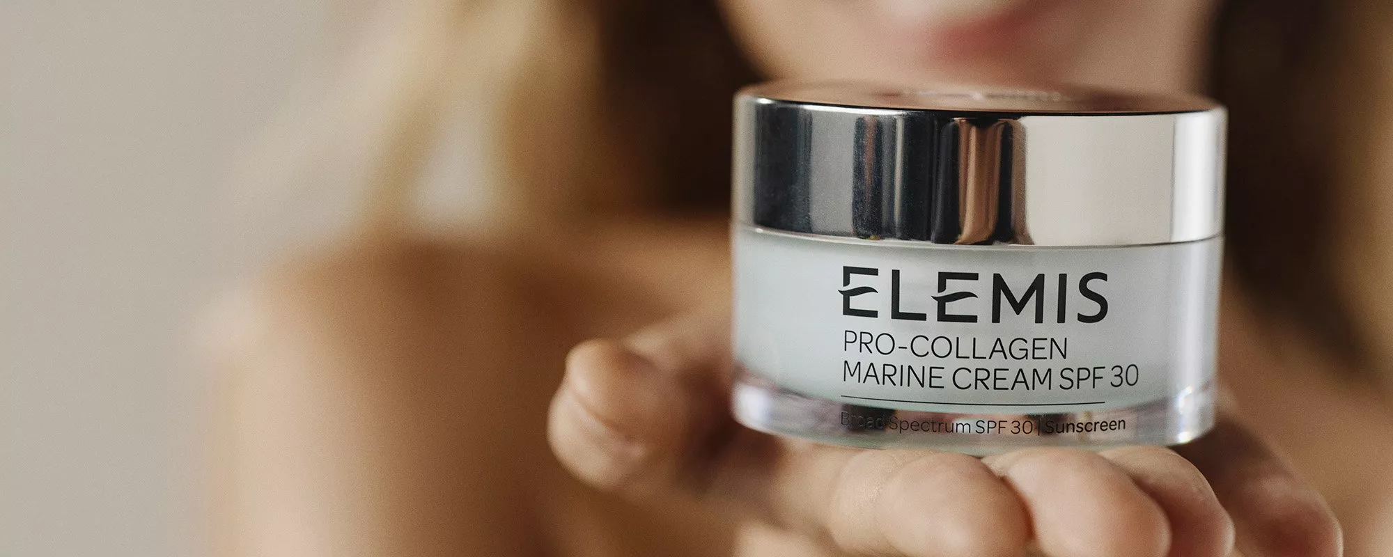 Close-up of Elemis Pro-Collagen Marine Cream SPF 30 held in hand, showcasing skincare product details.