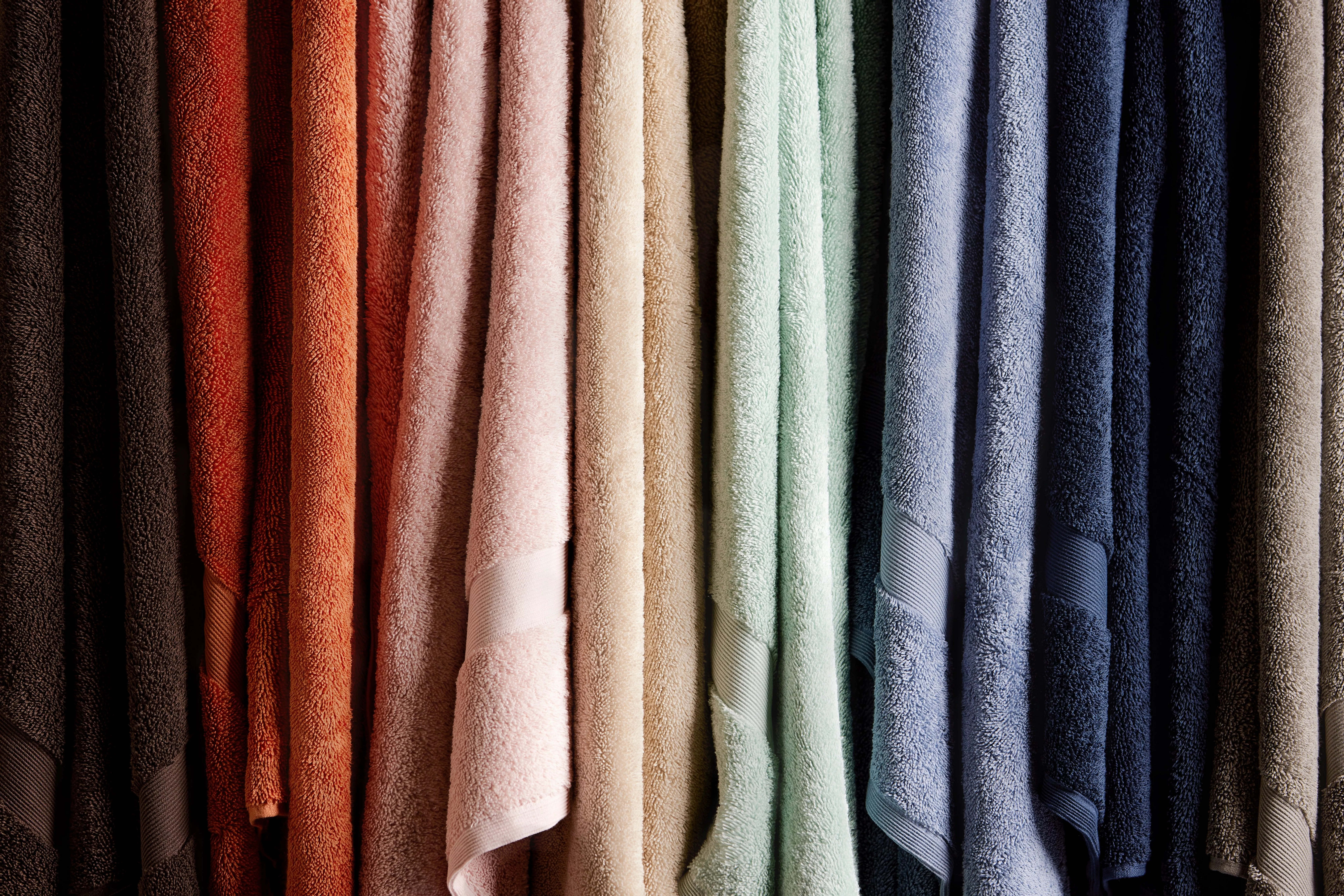 Colourful cotton bath towels hanging on a rail, plush textured bathroom linens in warm and cool tones