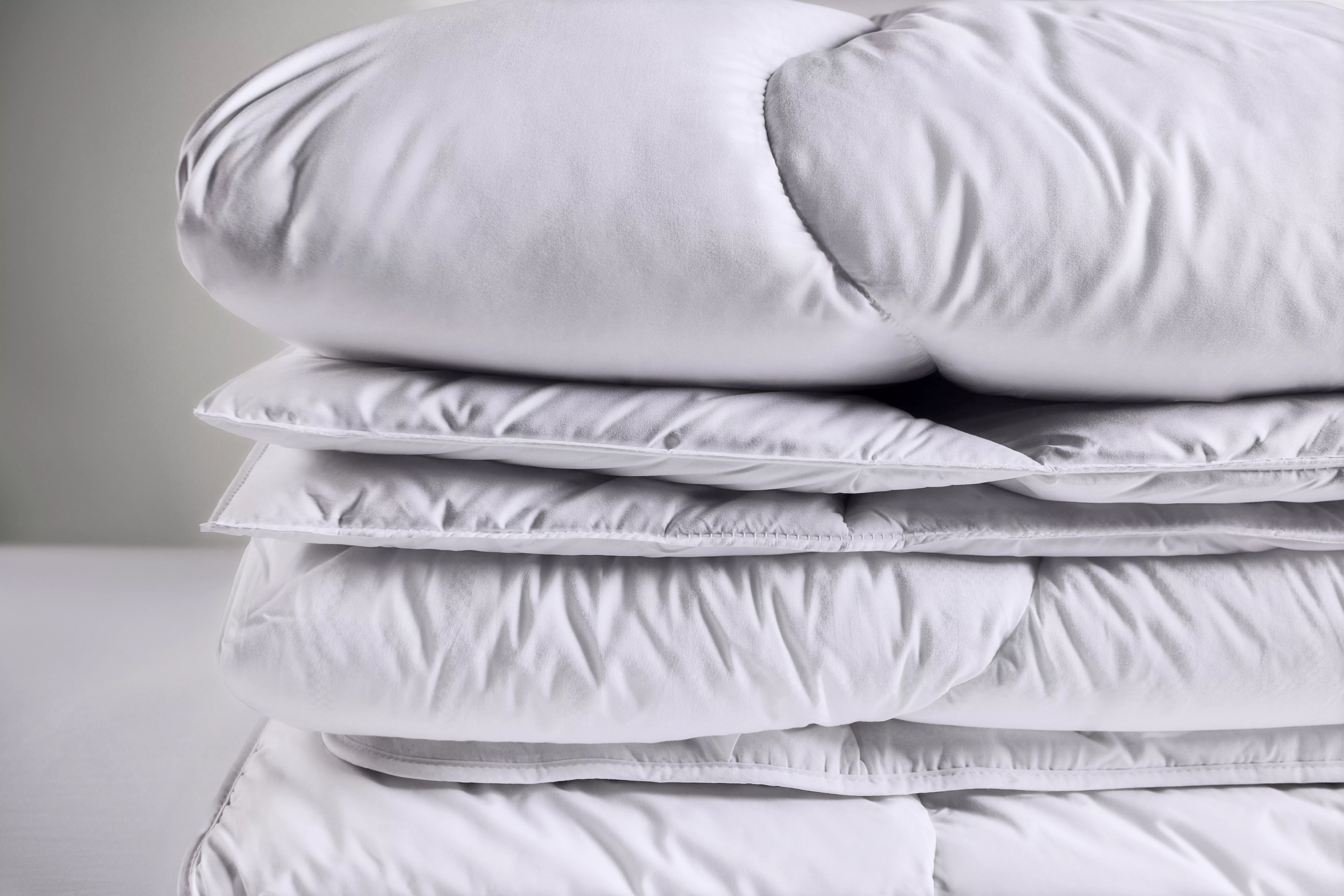 Stack of white pillows and duvets, soft bedding set for cosy bedroom sleep comfort and home textile decor
