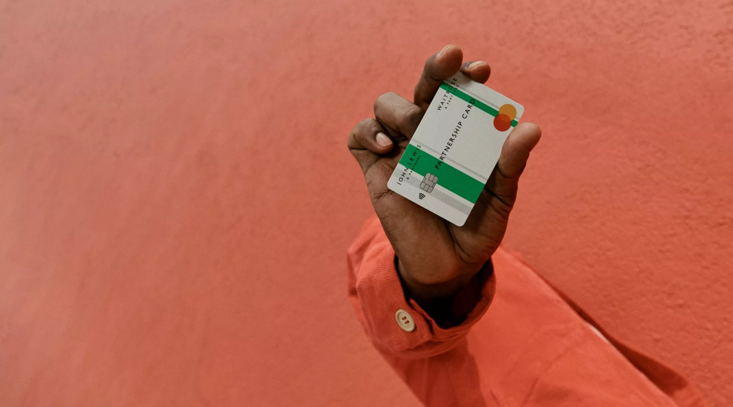 Hand holding a bank card against a coral wall background, modern contactless payment and finance concept photo