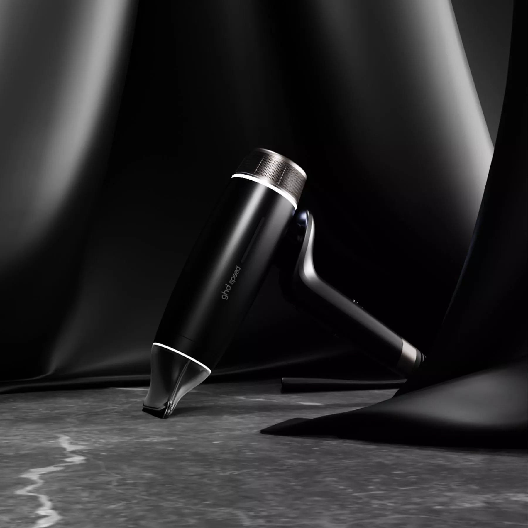 Sleek black GHD hairstyling tool on dark satin backdrop, luxury hair care product photography close-up