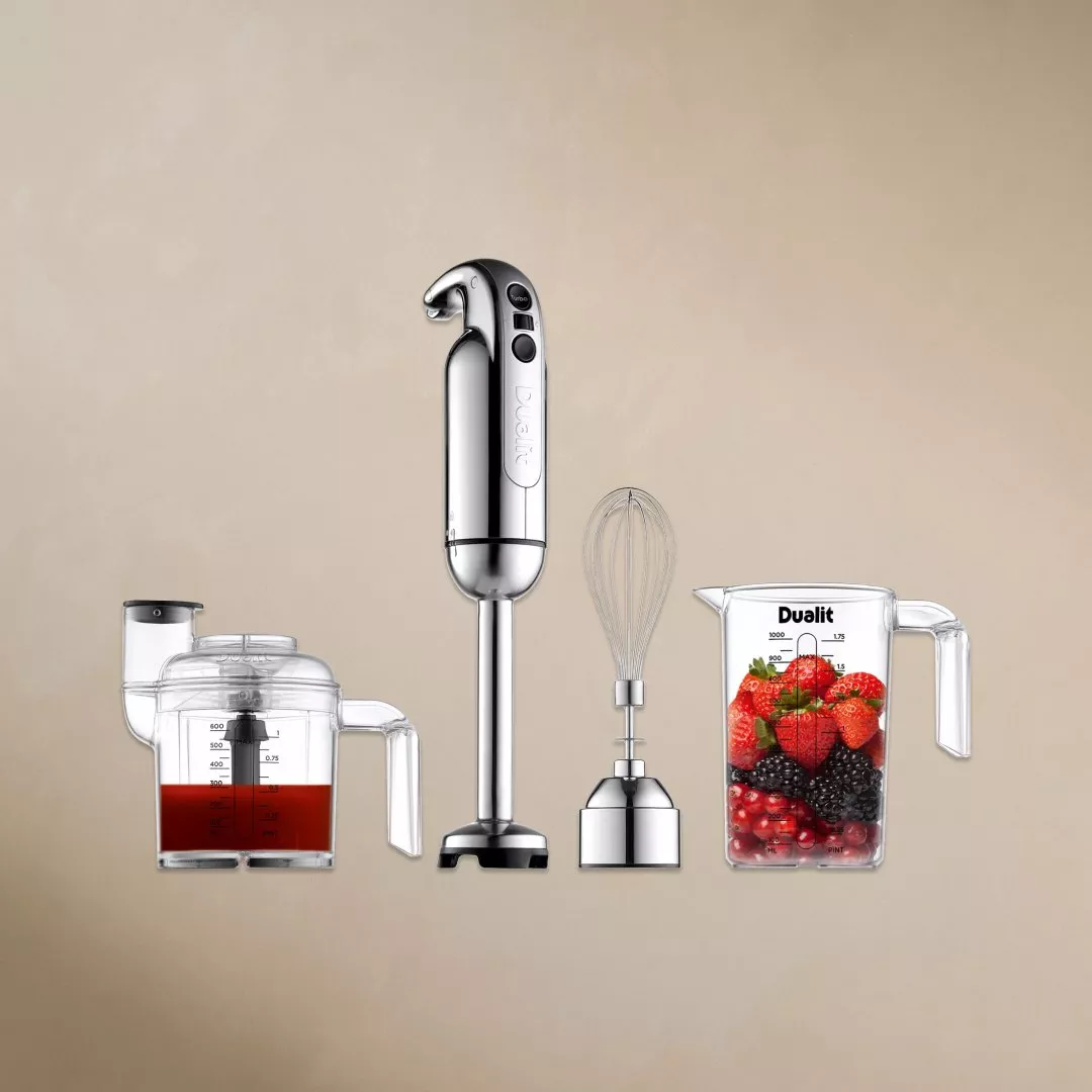 Sleek chrome hand mixer with attachments on a beige background, showcasing modern kitchen appliance design.