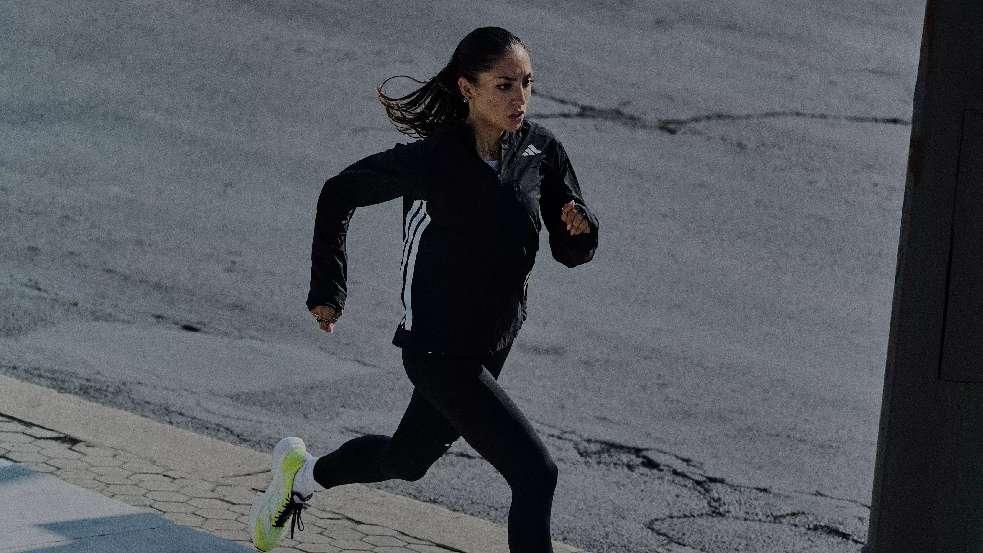 woman running wearing an adidas brand jacket, leggings and trainers