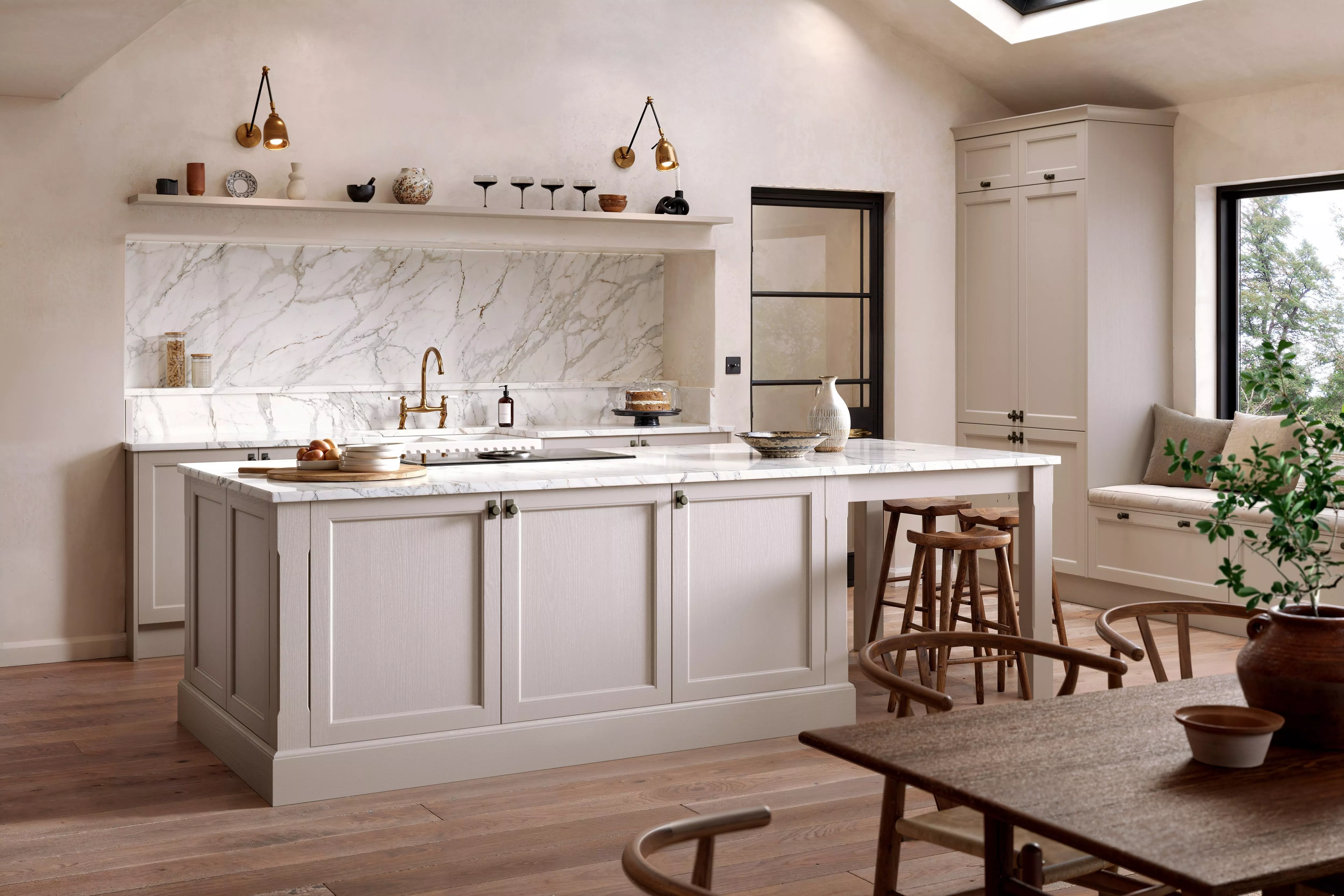 Modern kitchen with marble countertops, light cabinetry, and wooden accents. Features island seating and natural lighting.