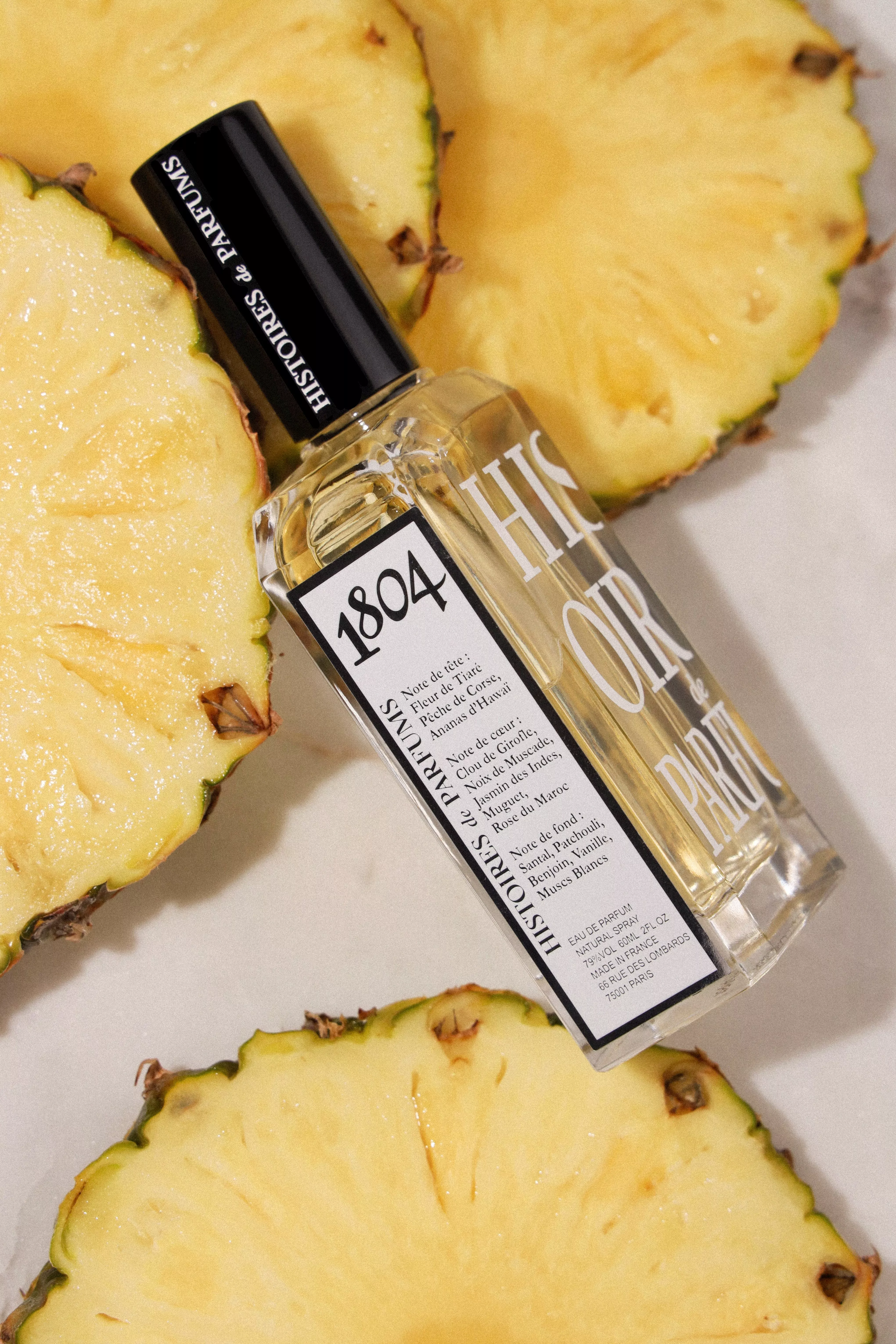 1804 Histoires de Parfums perfume bottle beside sliced pineapple, tropical fragrance product photography close-up