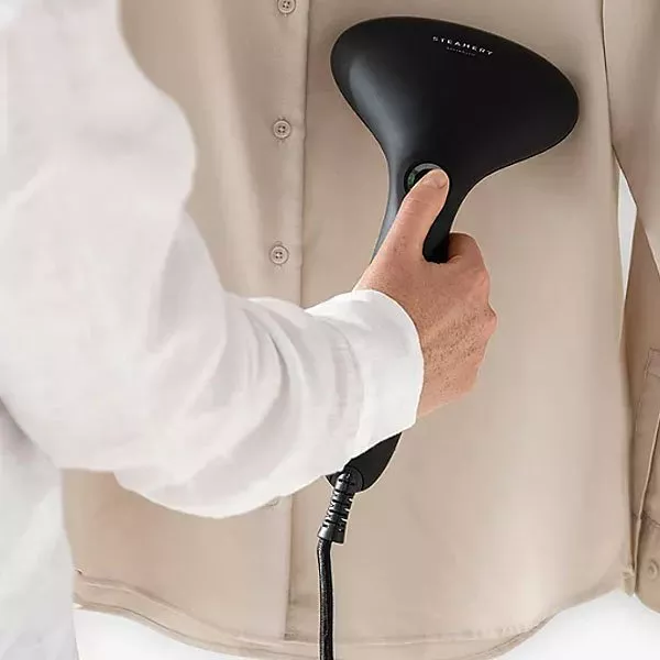 Person steaming a shirt with a garment steamer