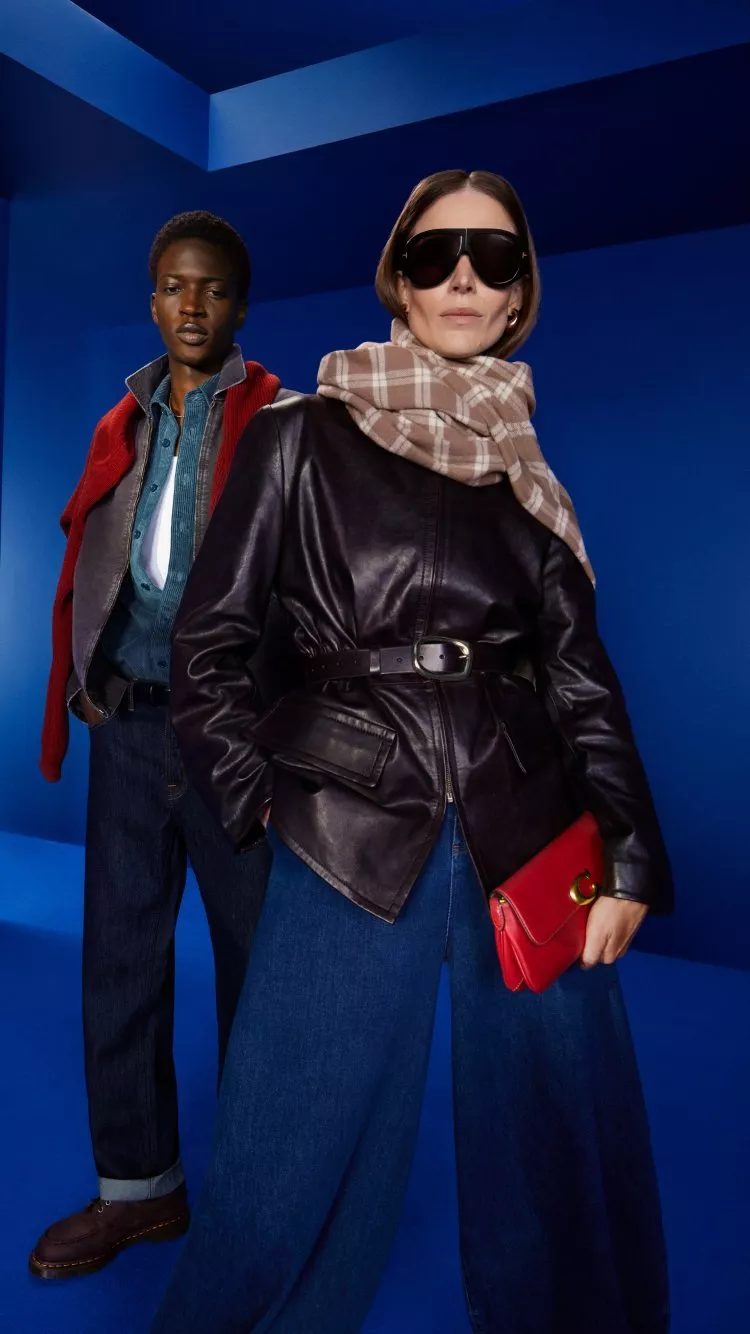 Two fashion models in denim jackets and jeans posing in a studio with bold green and blue geometric walls