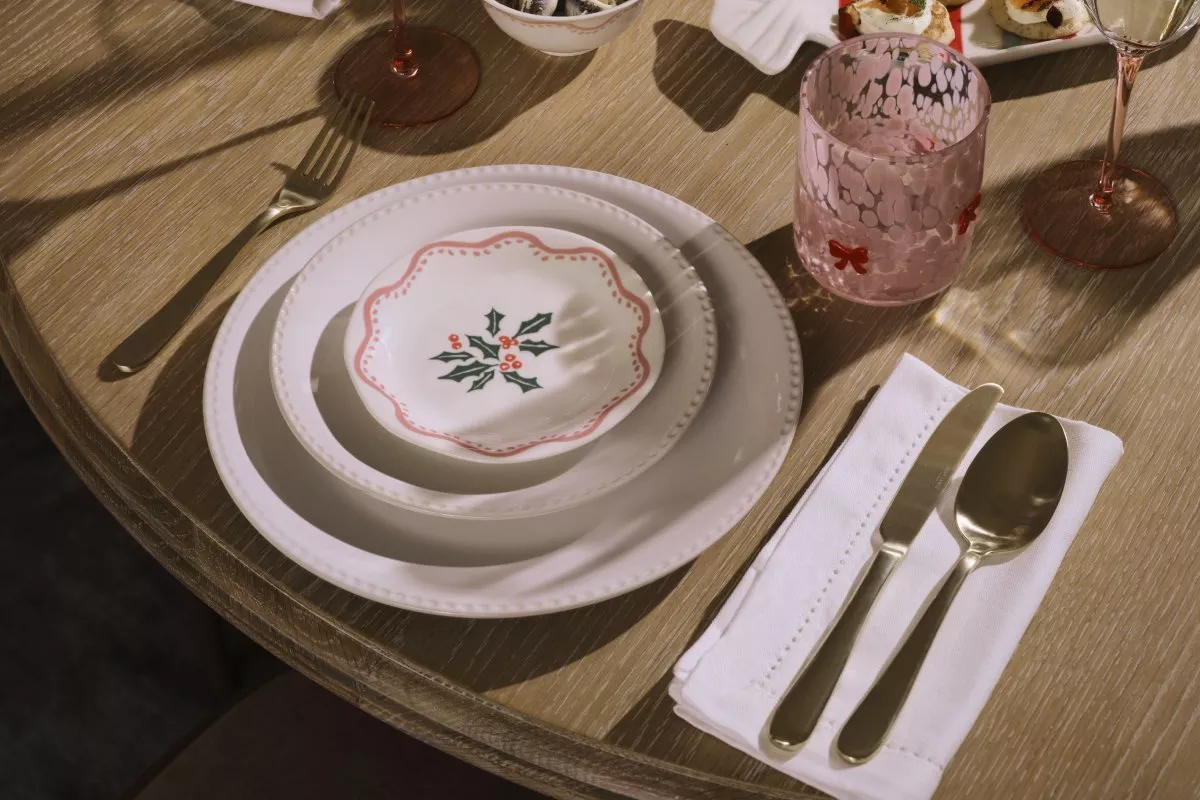 Elegant white dinner plate setting with a small, holly-decorated holiday dish.