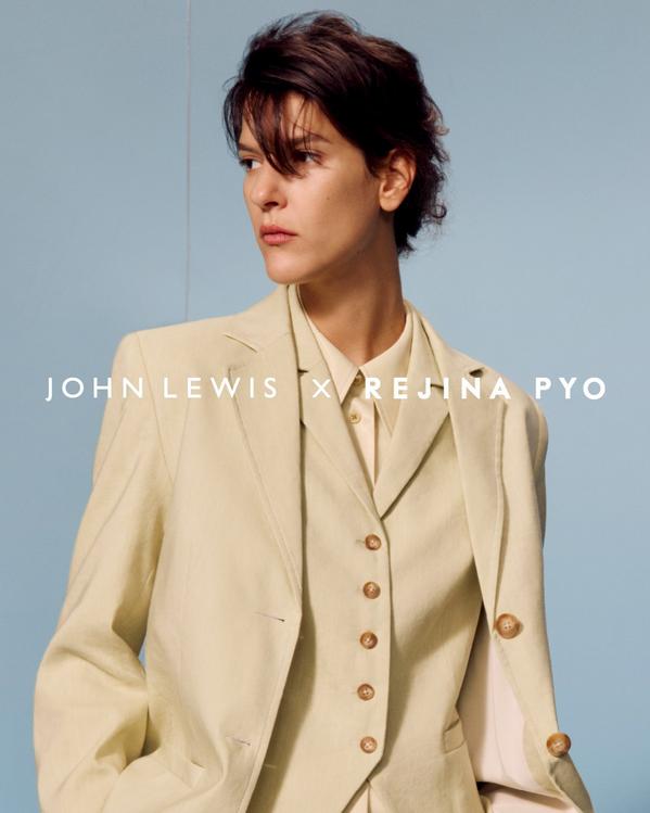 Model in beige tailored suit from John Lewis x Rejina Pyo collection, fashion portrait against blue background